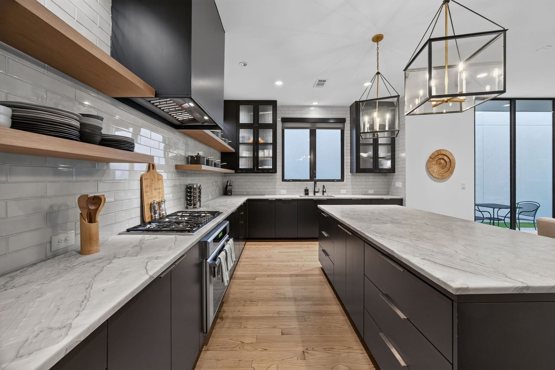 6002 Valley Forge Drive, Houston, TX 77057 Sleek modern kitchen featuring marble countertops, open shelving, and elegant pendant lighting, complemented by a spacious island and stylish cabinetry.