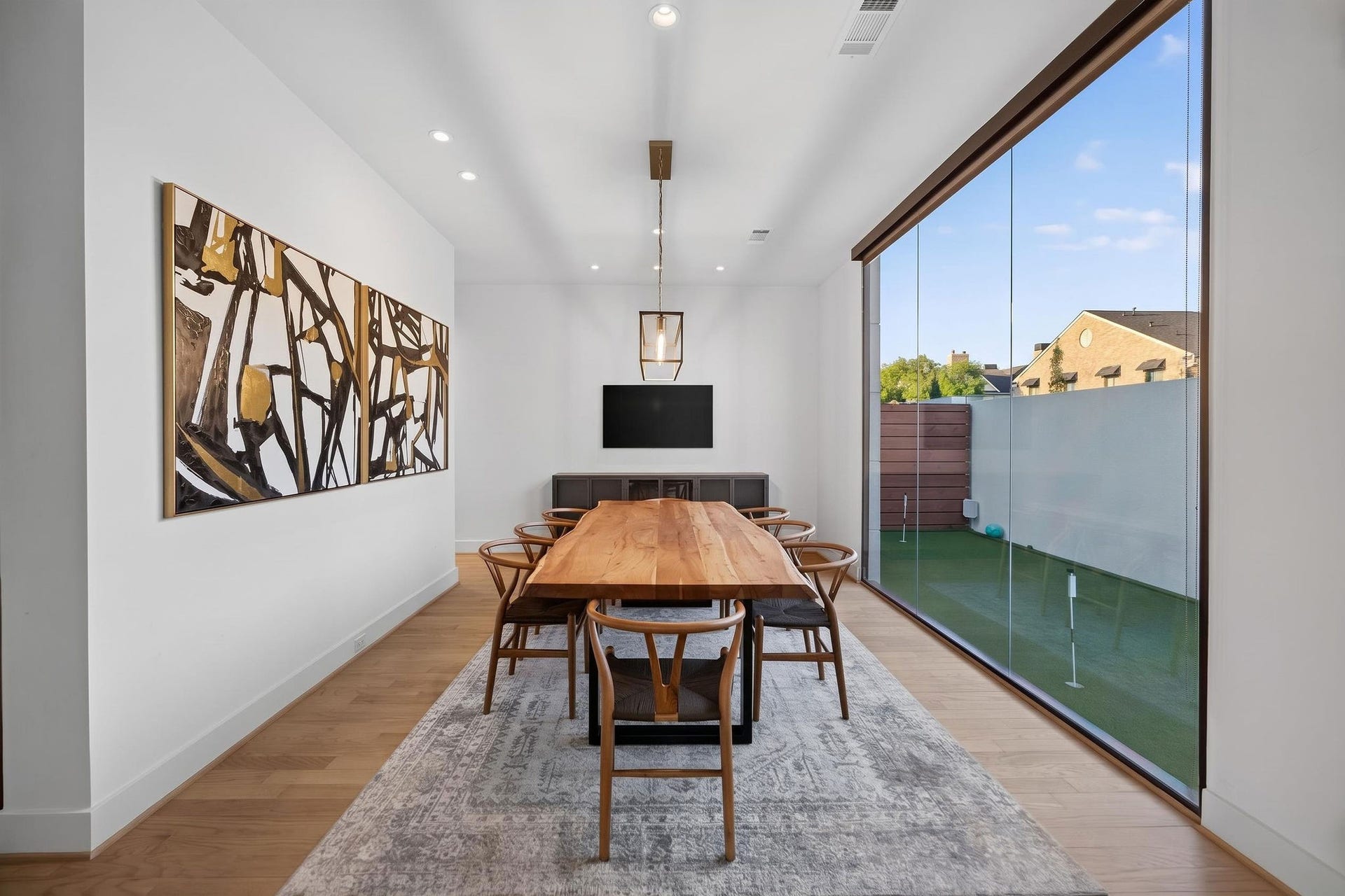 6002 Valley Forge Drive, Houston, TX 77057 Elegant dining area with a modern wooden table, chic chairs, and floor-to-ceiling windows offering abundant natural light and garden views.