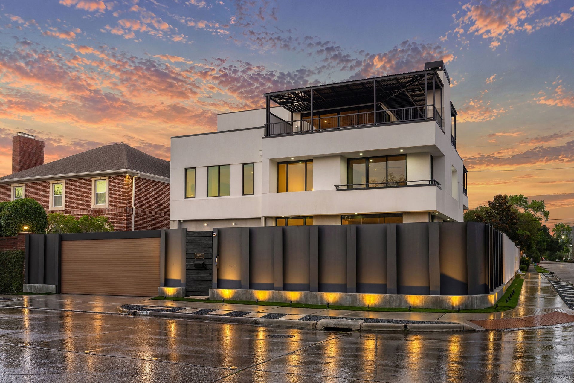 6002 Valley Forge Drive, Houston, TX 77057 Stunning modern architecture with sleek lines, expansive windows, and a spacious rooftop terrace, all set against a vibrant sunset sky.