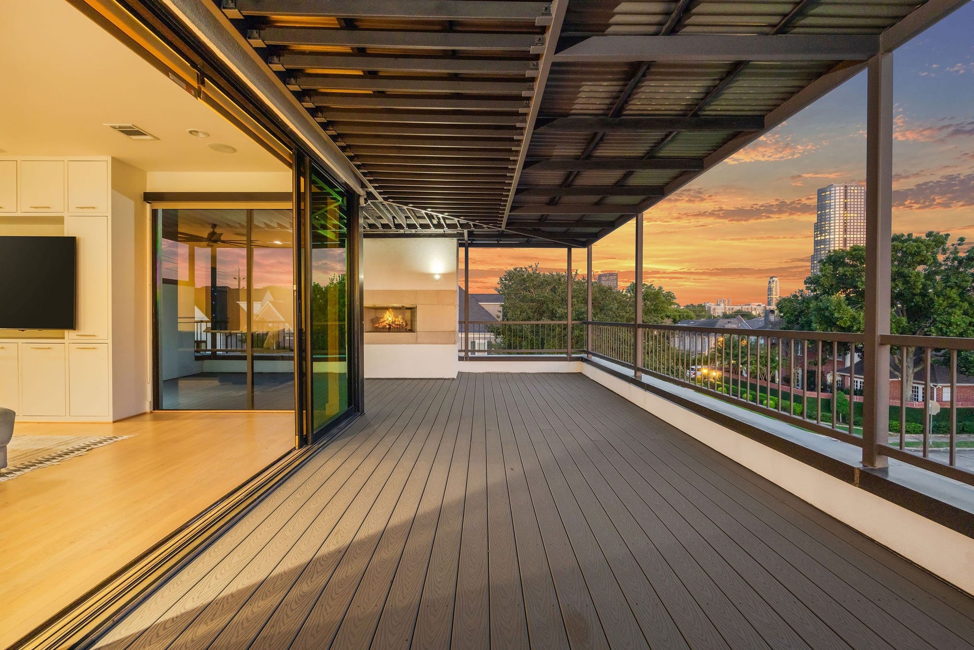6002 Valley Forge Drive, Houston, TX 77057 Spacious covered balcony with stunning sunset views, seamlessly connected to the elegant interior through expansive sliding glass doors.