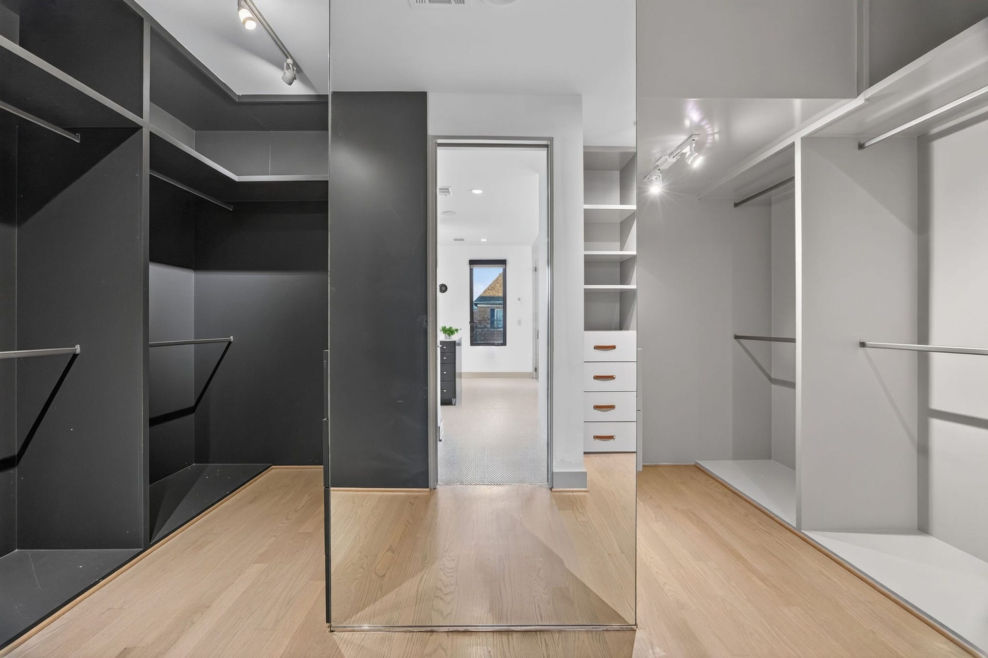 6002 Valley Forge Drive, Houston, TX 77057 Spacious walk-in closet with sleek black and white shelving, ample hanging space, and modern track lighting.
