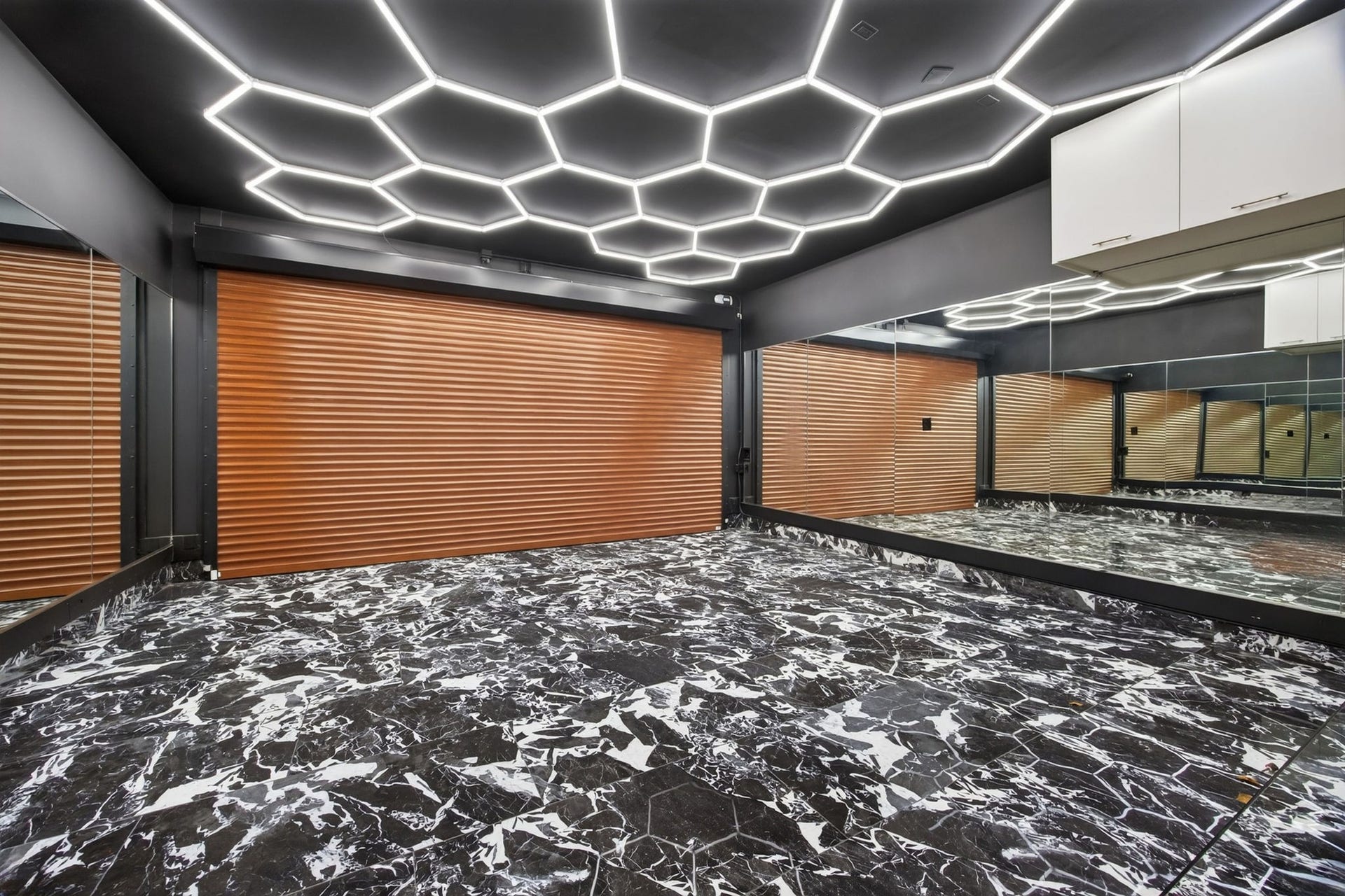 6002 Valley Forge Drive, Houston, TX 77057 Experience a modern, stylish space featuring a striking geometric ceiling with LED lighting, elegant marble-patterned flooring, and expansive mirrors for a sophisticated ambiance.
