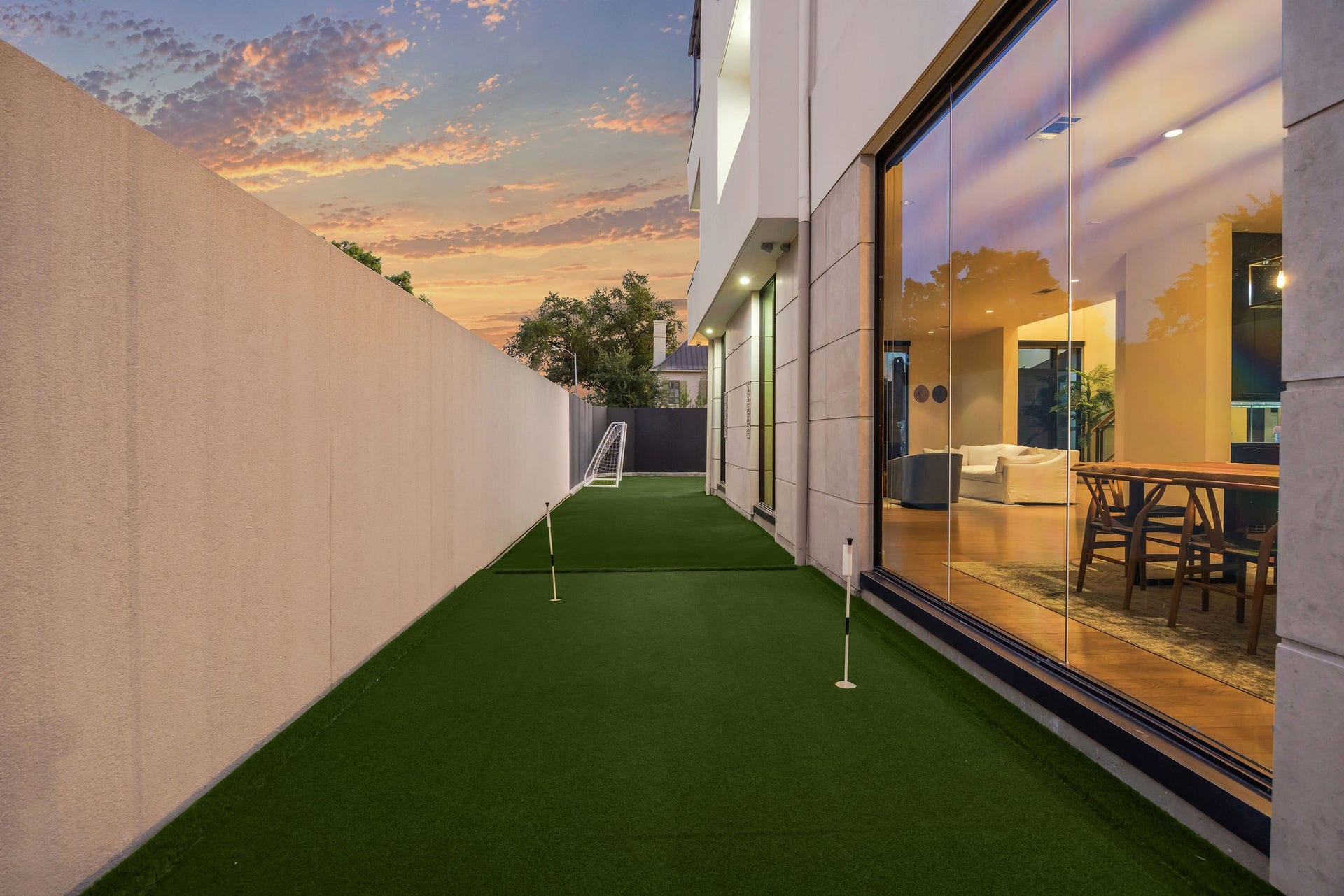 6002 Valley Forge Drive, Houston, TX 77057 Modern home with a sleek, glass-walled exterior overlooking a private putting green, perfect for relaxation and entertainment.