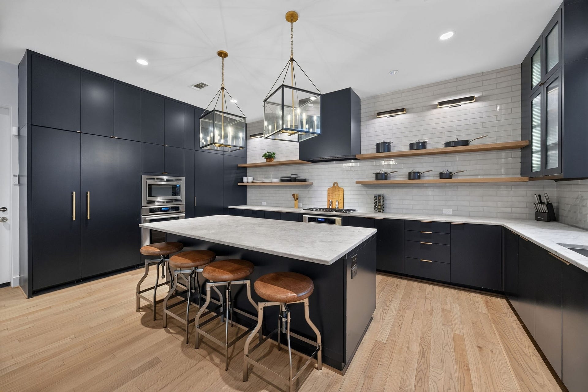 6002 Valley Forge Drive, Houston, TX 77057 A large island featuring marble countertops and stylish pendant lighting.