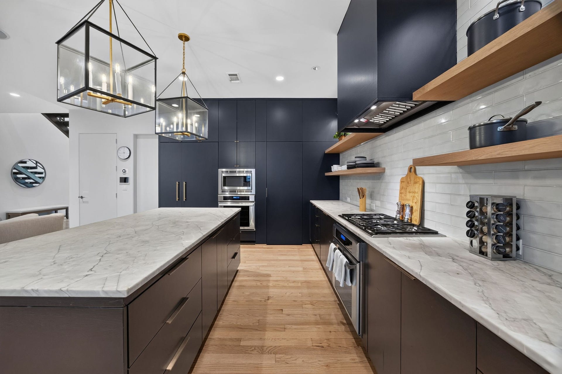 6002 Valley Forge Drive, Houston, TX 77057 Modern kitchen with sleek navy cabinetry, marble countertops, and elegant pendant lighting, featuring a spacious island and state-of-the-art appliances.