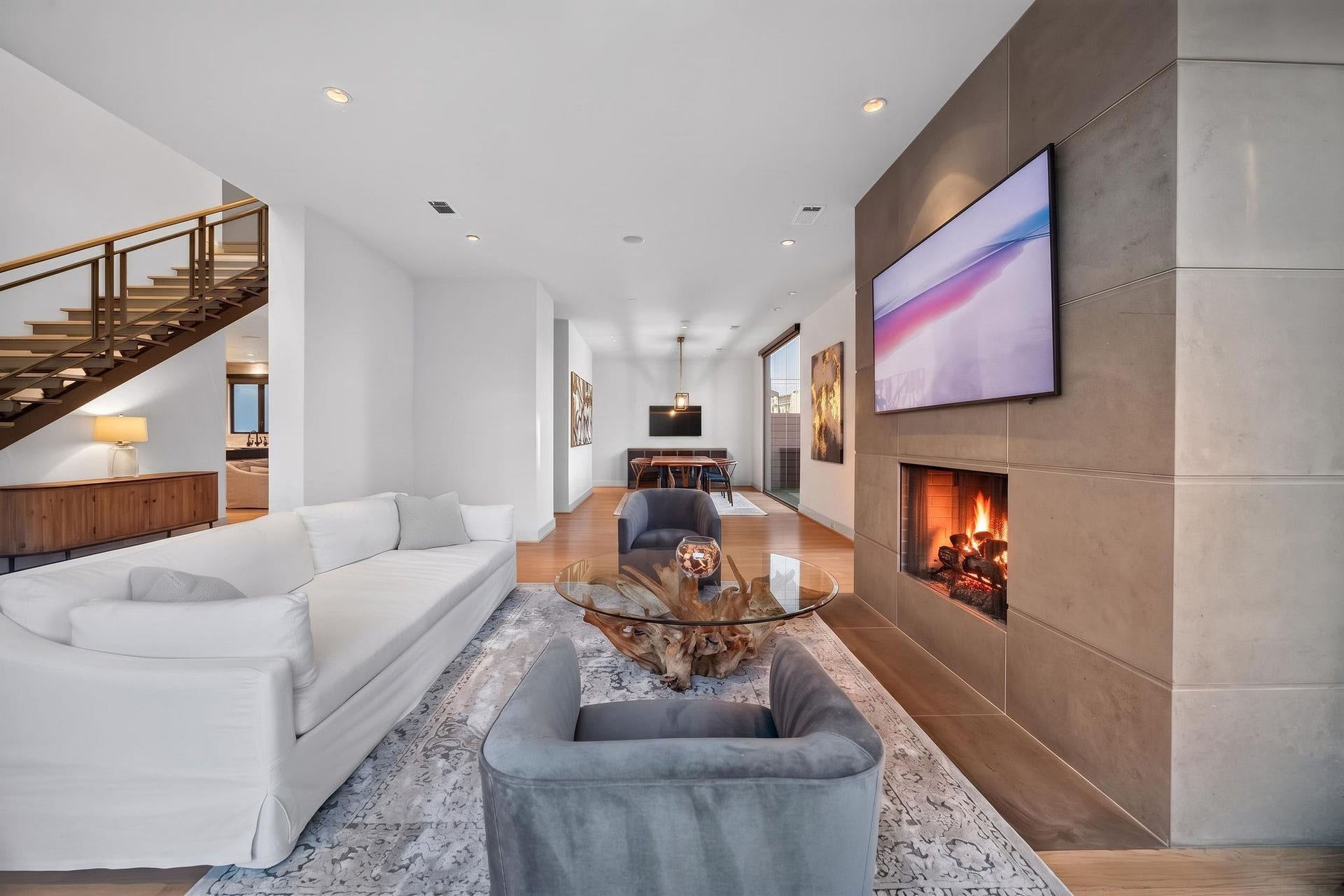 6002 Valley Forge Drive, Houston, TX 77057 Elegant open-concept living space featuring a modern fireplace, sleek staircase, and stylish seating area, seamlessly leading into a bright dining area.