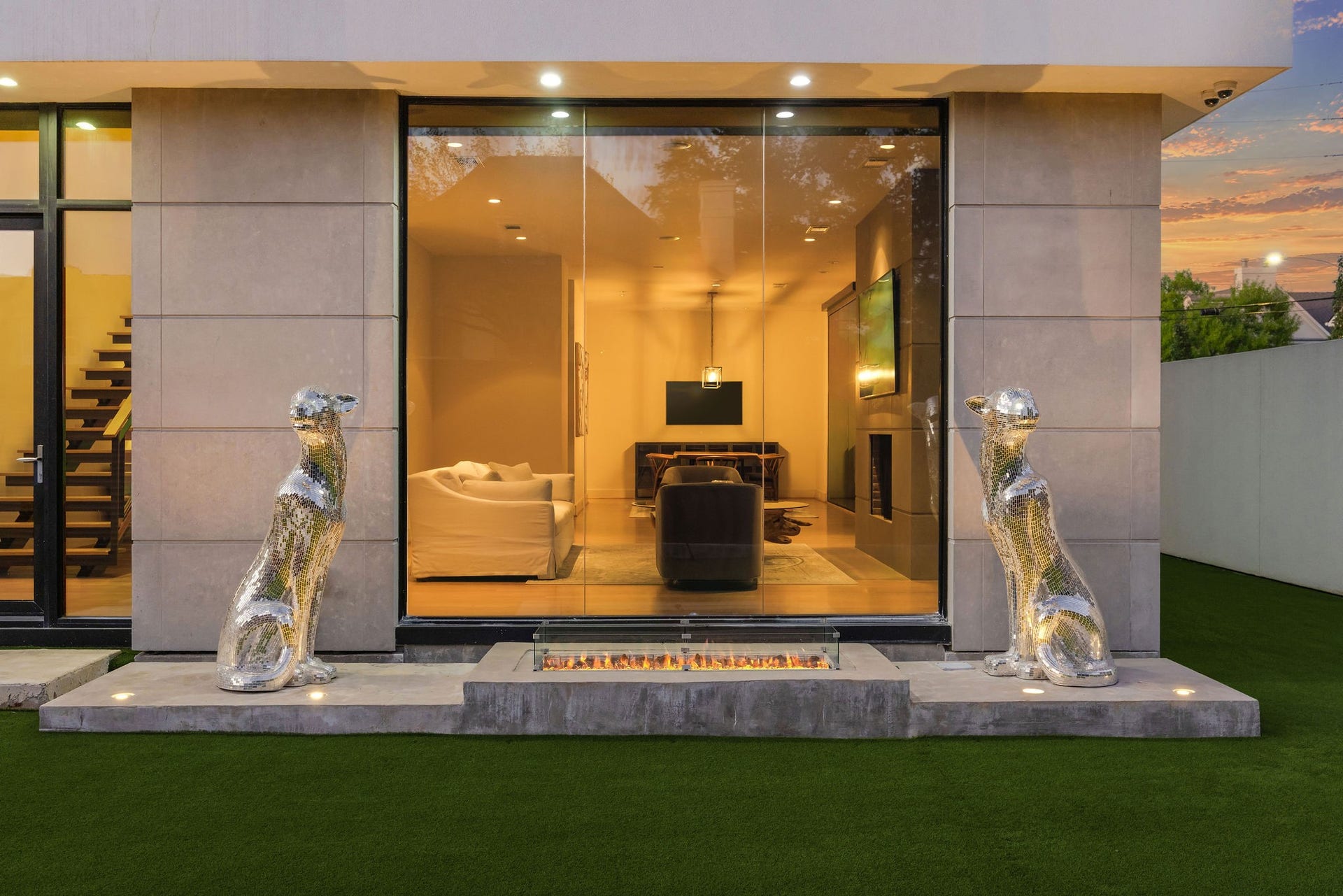 6002 Valley Forge Drive, Houston, TX 77057 Elegant modern home with expansive glass doors, showcasing a stylish interior and unique metallic sculptures flanking the entrance.