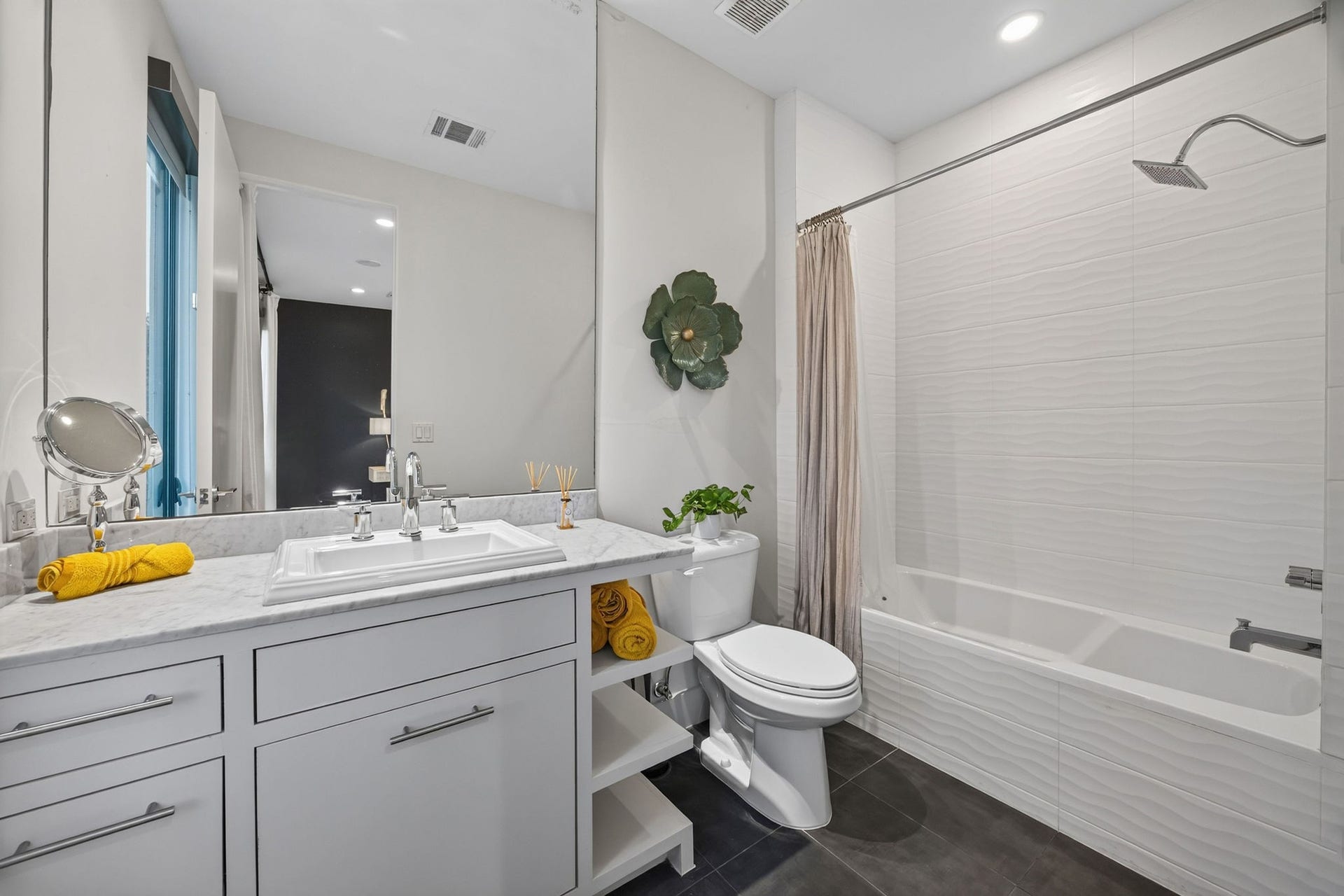 6002 Valley Forge Drive, Houston, TX 77057 Bright and modern bathroom with a sleek vanity, ample storage, and a stylish bathtub with a rainfall showerhead.