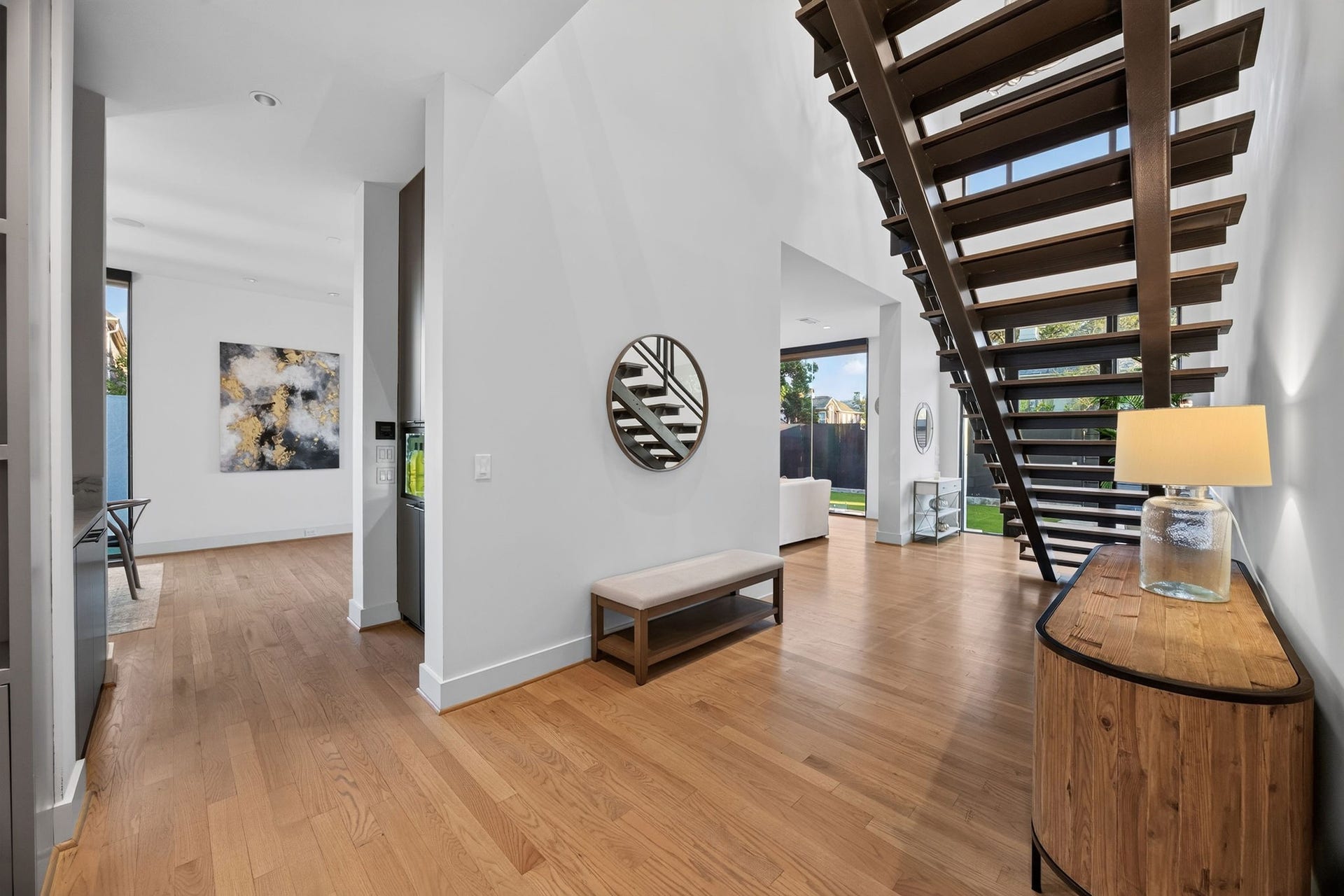6002 Valley Forge Drive, Houston, TX 77057 Stunning entryway with sleek wood flooring and a striking modern staircase, leading to a bright, open living area filled with natural light.