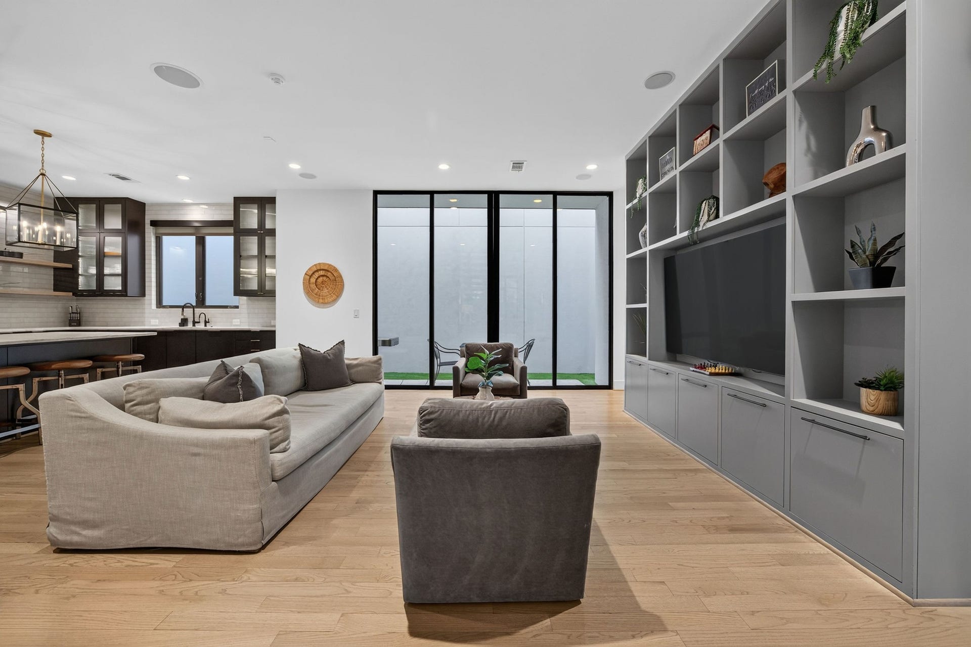 6002 Valley Forge Drive, Houston, TX 77057 Spacious and modern living area featuring sleek built-in shelving, a large flat-screen TV, and an open concept that flows seamlessly into the elegant kitchen with a breakfast bar.