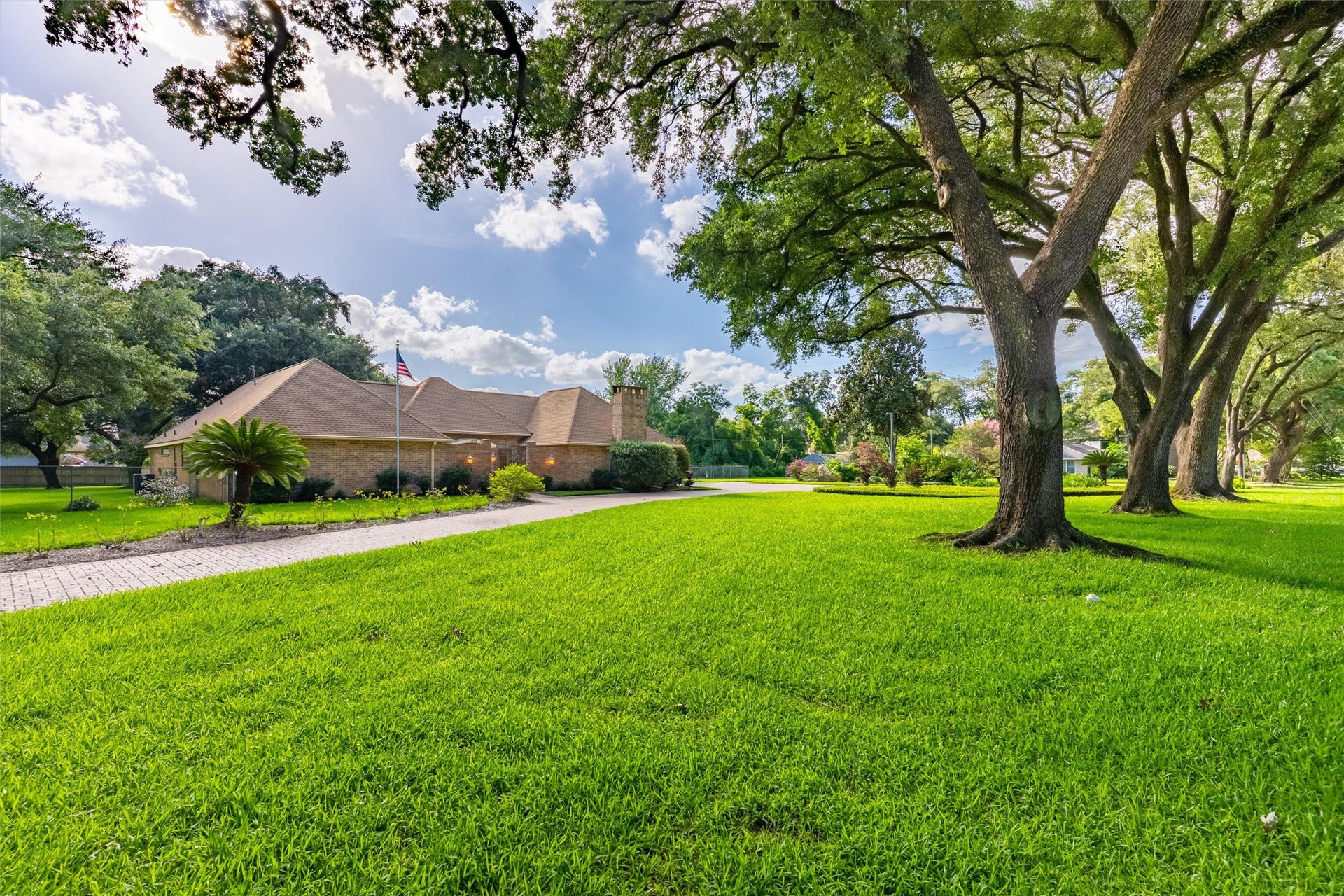 1715 Avenue D, Katy, TX 77493 A picturesque canopy of towering oak trees stretches overhead as one of three paved driveways winds through 1.71 acres of beautifully landscaped grounds, creating a grand arrival experience.