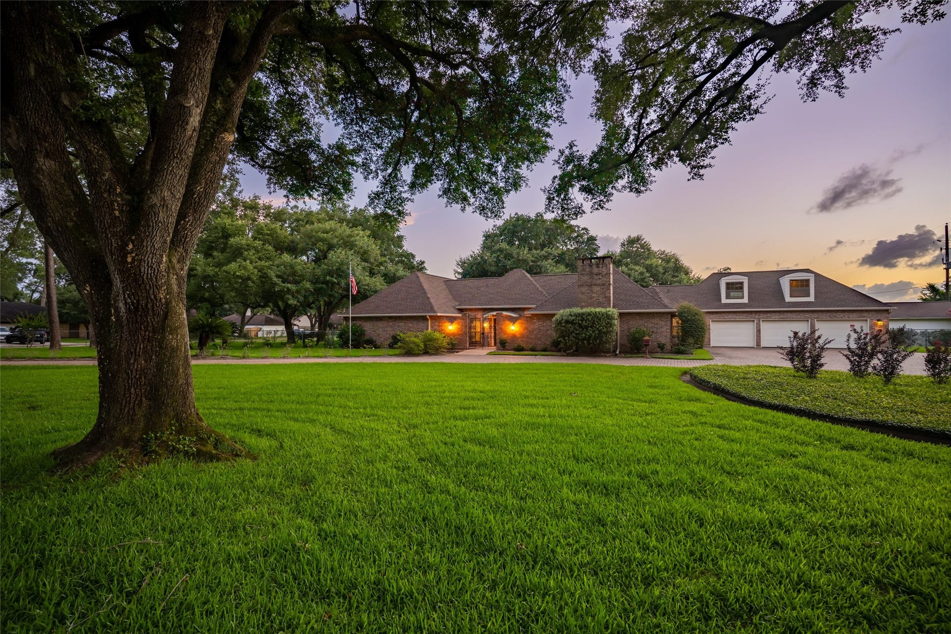 1715 Avenue D, Katy, TX 77493 From this twilight evening perspective, timeless architecture, pristine landscaping and the three-car garage come together to create an unforgettable estate.