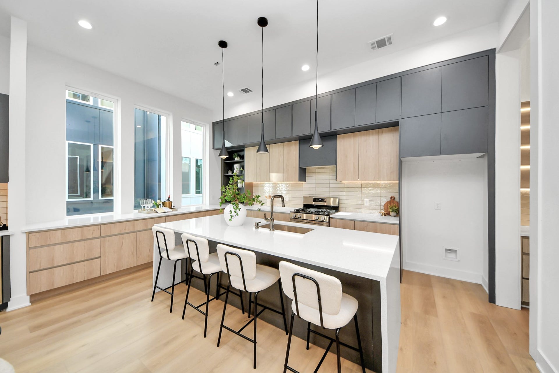 1603 W 25th Street, Houston, TX 77008 Modern kitchen featuring a spacious waterfall island, pendant lighting, two-tone cabinetry, and stainless steel appliances.