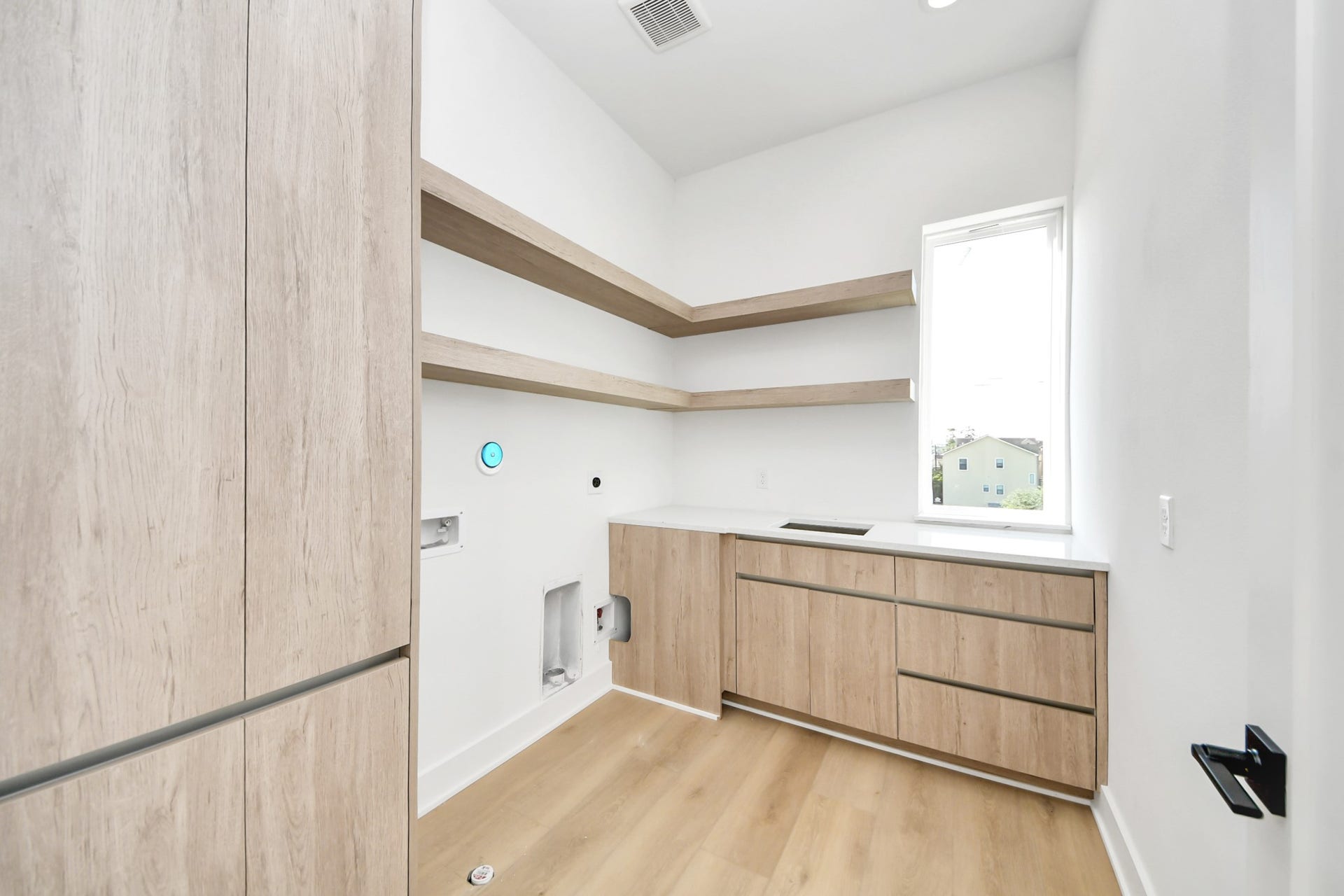 1603 W 25th Street, Houston, TX 77008 Third-floor laundry room with built-in cabinetry, shelving, and a utility sink.