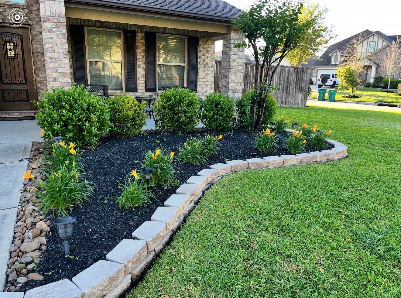 2806 Bretton Woods Drive, Conroe, TX 77301 Charming home with a well-maintained front yard featuring a brick facade, lush green lawn, and a beautifully landscaped garden bed with vibrant flowers and shrubs, lined with stone edging.