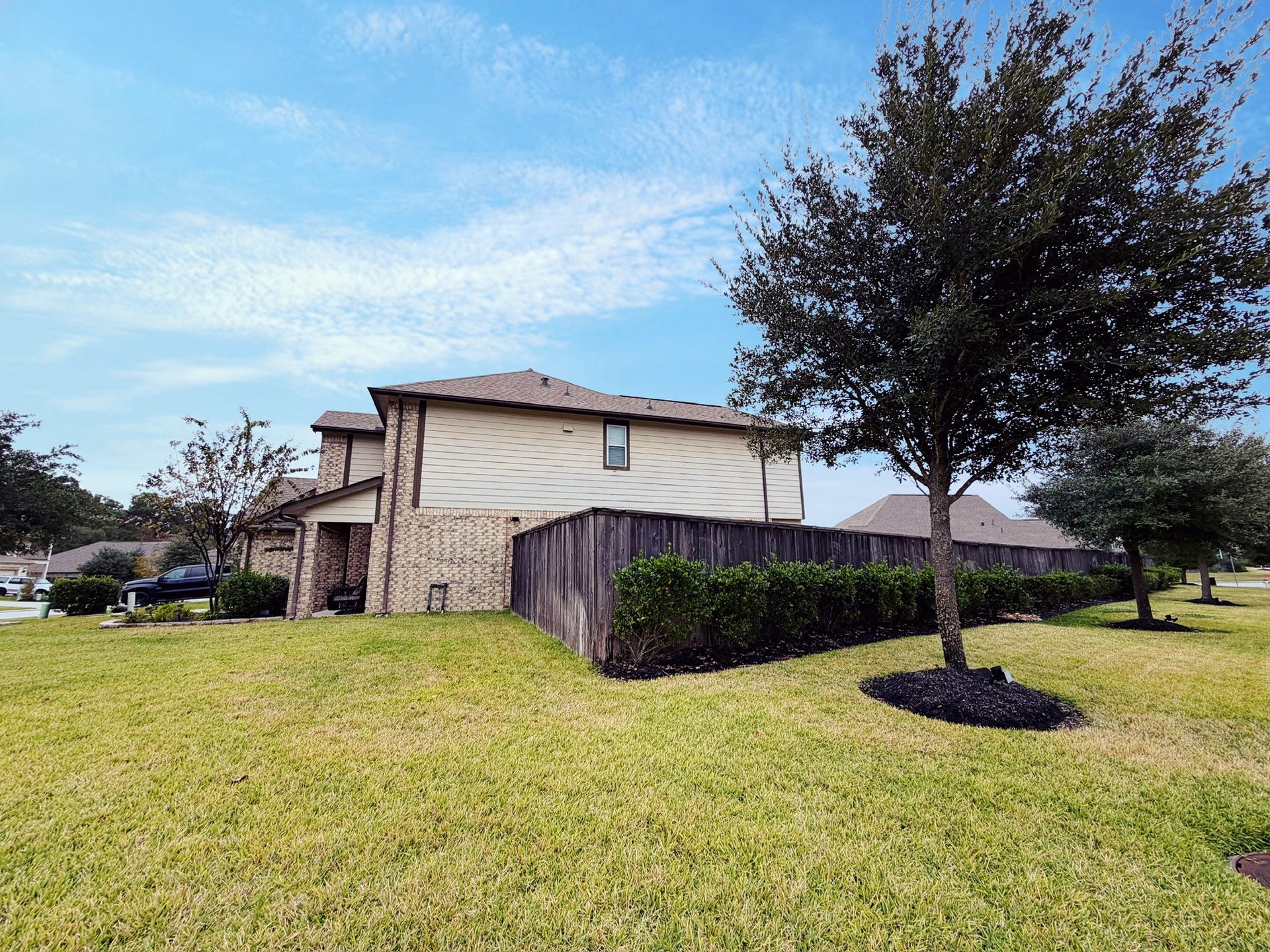 2806 Bretton Woods Drive, Conroe, TX 77301 This photo shows a two-story brick and siding house with a well-maintained lawn and surrounding trees, offering a spacious corner lot with ample greenery.