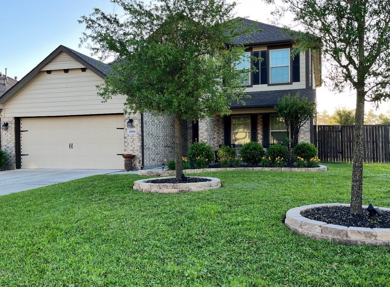 2806 Bretton Woods Drive, Conroe, TX 77301 This charming two-story home features a classic brick facade with modern siding, a spacious two-car garage, and a well-maintained front lawn. Mature trees and landscaped shrubbery enhance its curb appeal, while a wooden privacy fence outlines the property.