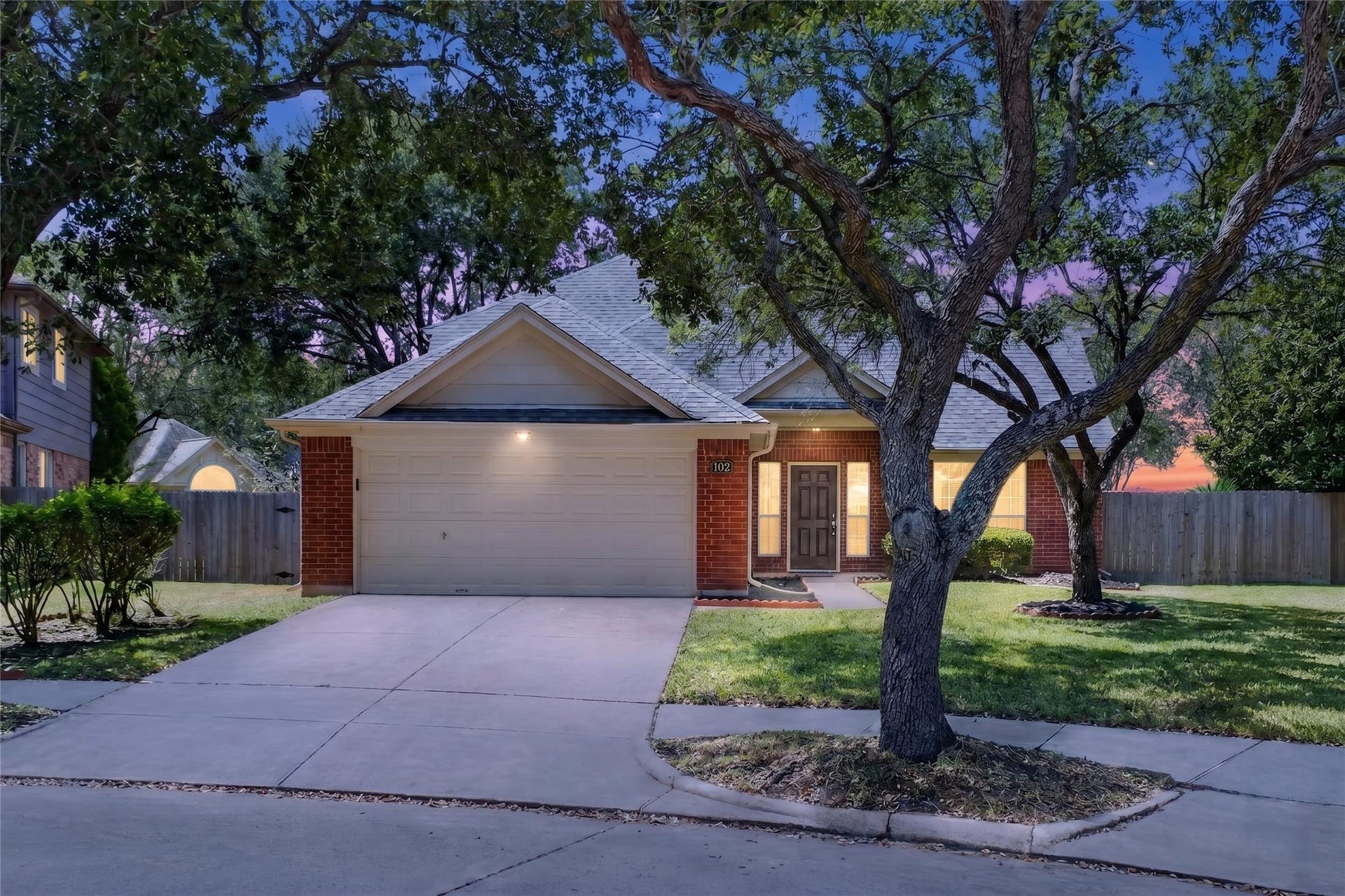 102 Lissa Lane, Sugar Land, TX 77479 Charming single-story home with a welcoming front porch, nestled among mature trees and featuring a spacious two-car garage.