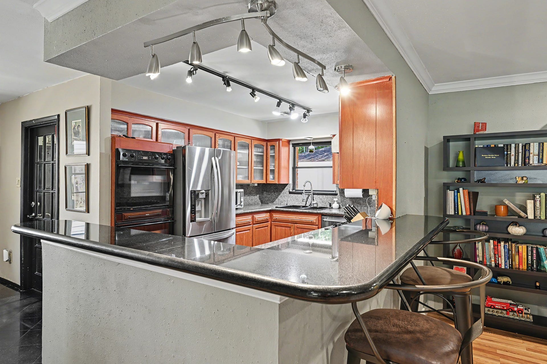 Granite kitchen with breakfast bar and many glass front cabinets.