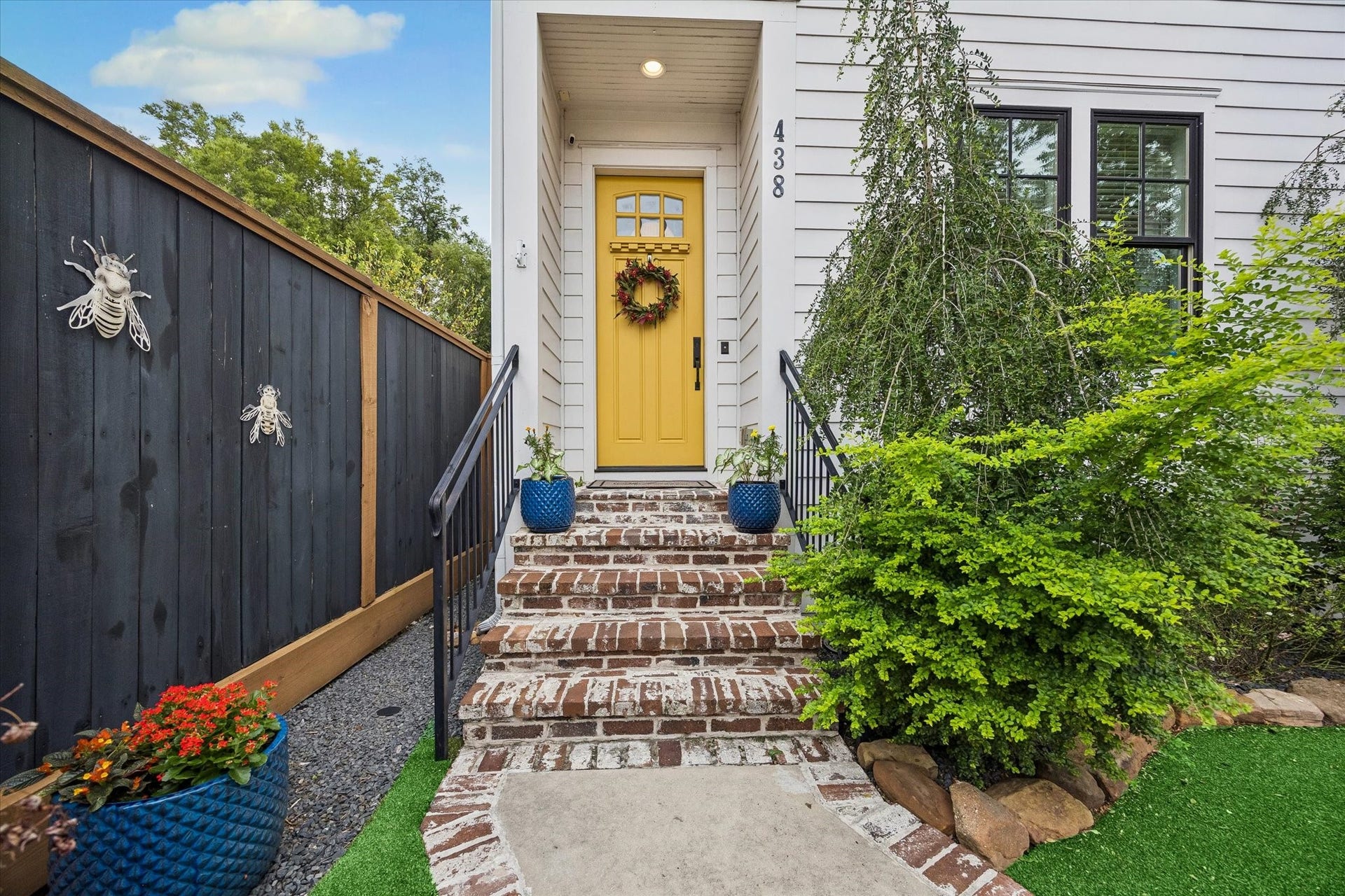 438 W 28th Street, Houston, TX 77008 Brick steps lead to a welcoming covered front porch and a sunny yellow door that adds a fun pop of personality, while the gated entry and lush landscaping make coming home feel extra special.