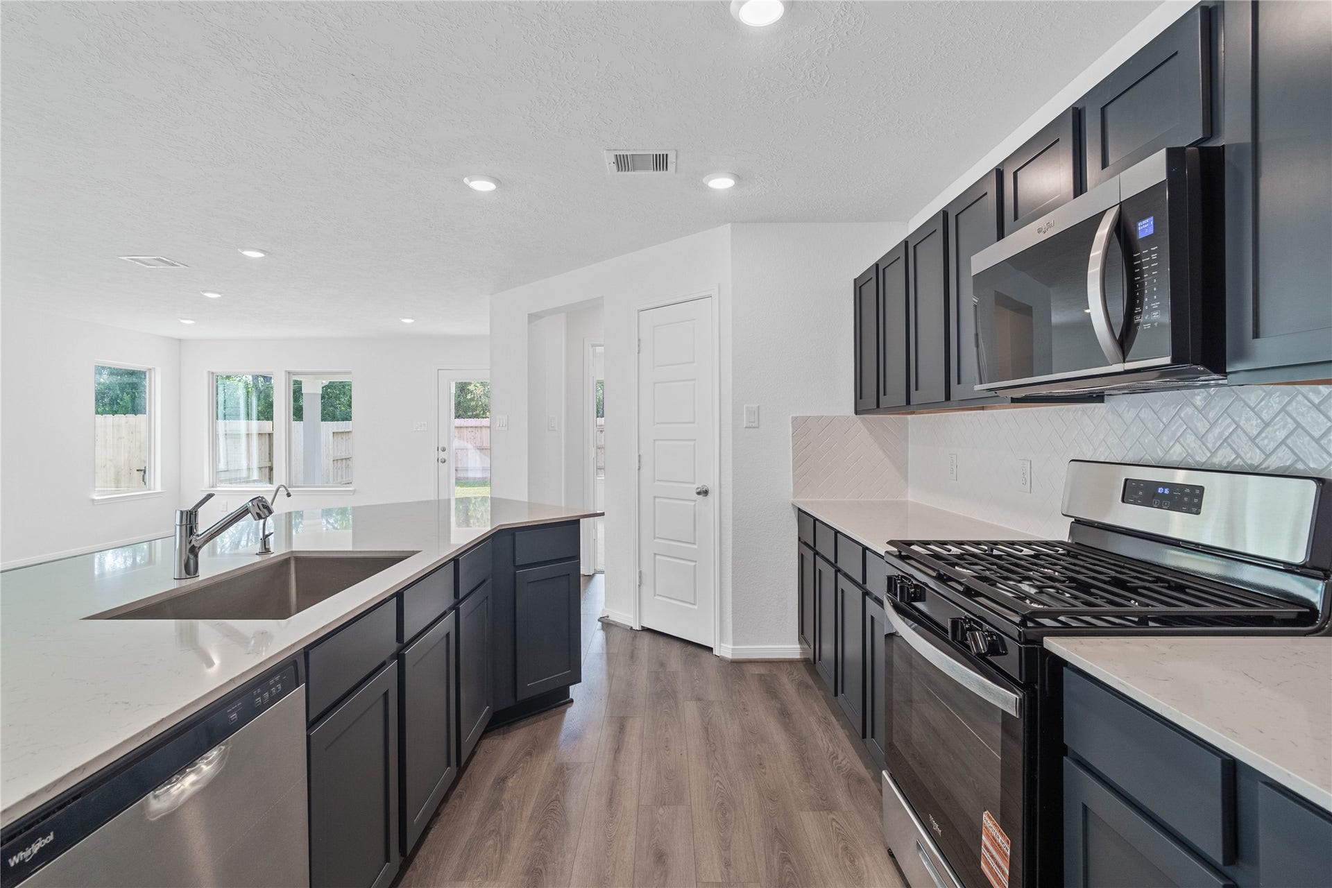 1710 Livadero Lane, Fresno, TX 77545 This bright, open kitchen is a chef's delight, complete with a large island, quartz countertops, stained Woodmont Dakota cabinets, Whirlpool stainless steel appliances, and modern Daltile backsplash.