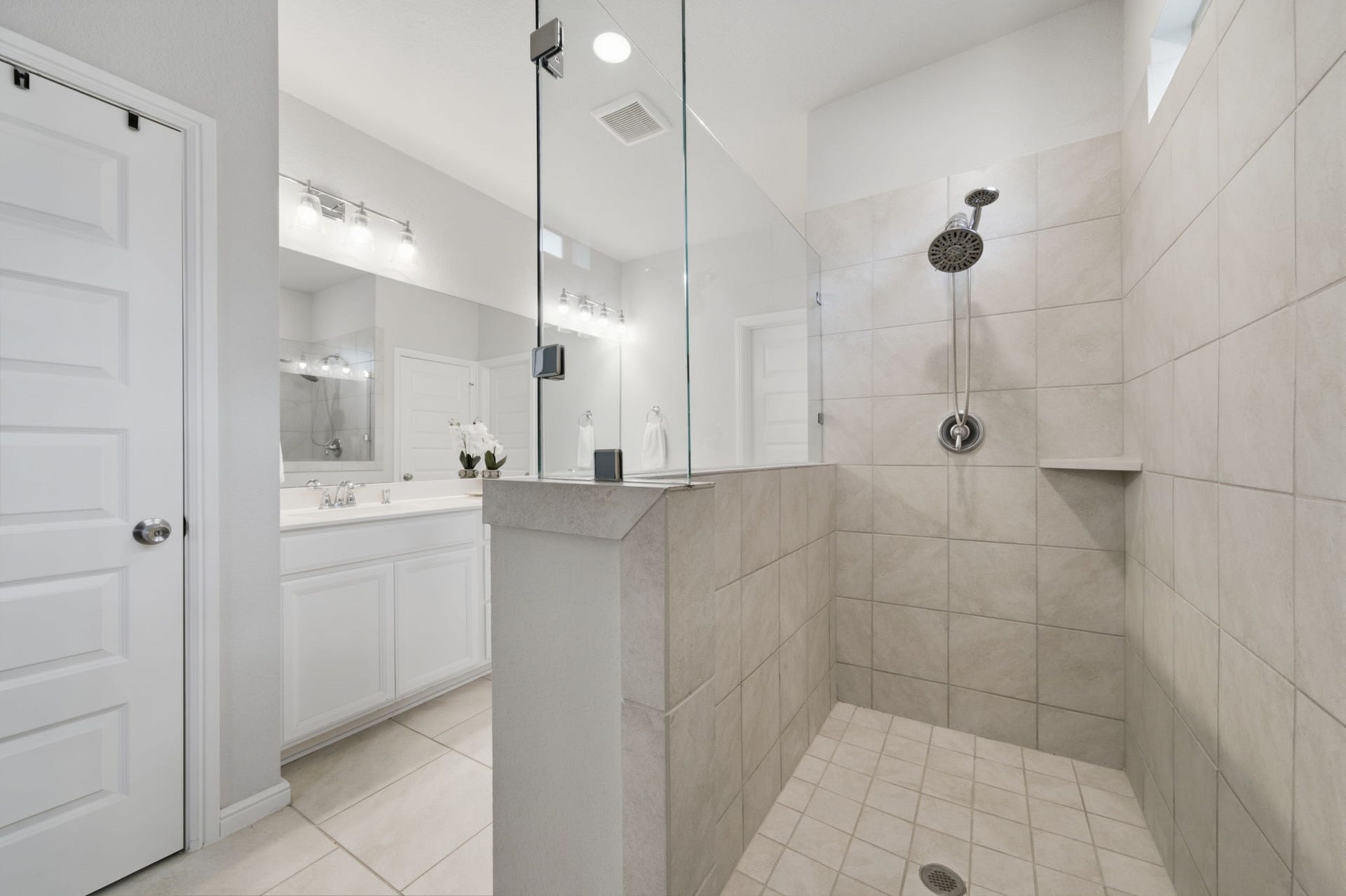 The walk-in shower has a storage nook and glass wall panel to allow for more light to come in.