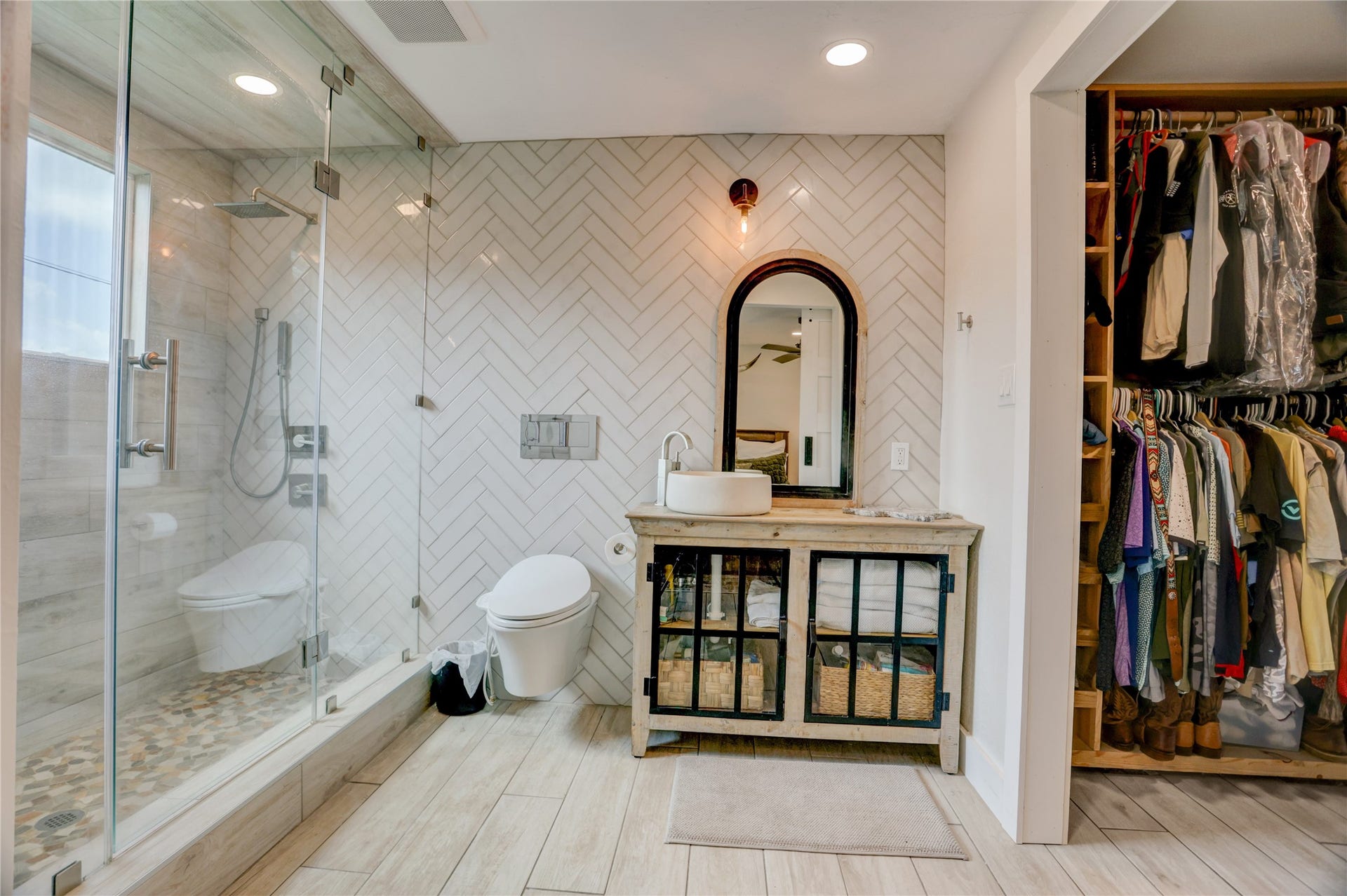 3311 Carmel Valley Drive, Missouri City, TX 77459 Primary Bathroom features a frameless glass walk in shower with designer tile, modern floating toilet, vessel sink vanity and stylish herringbone accent wall.