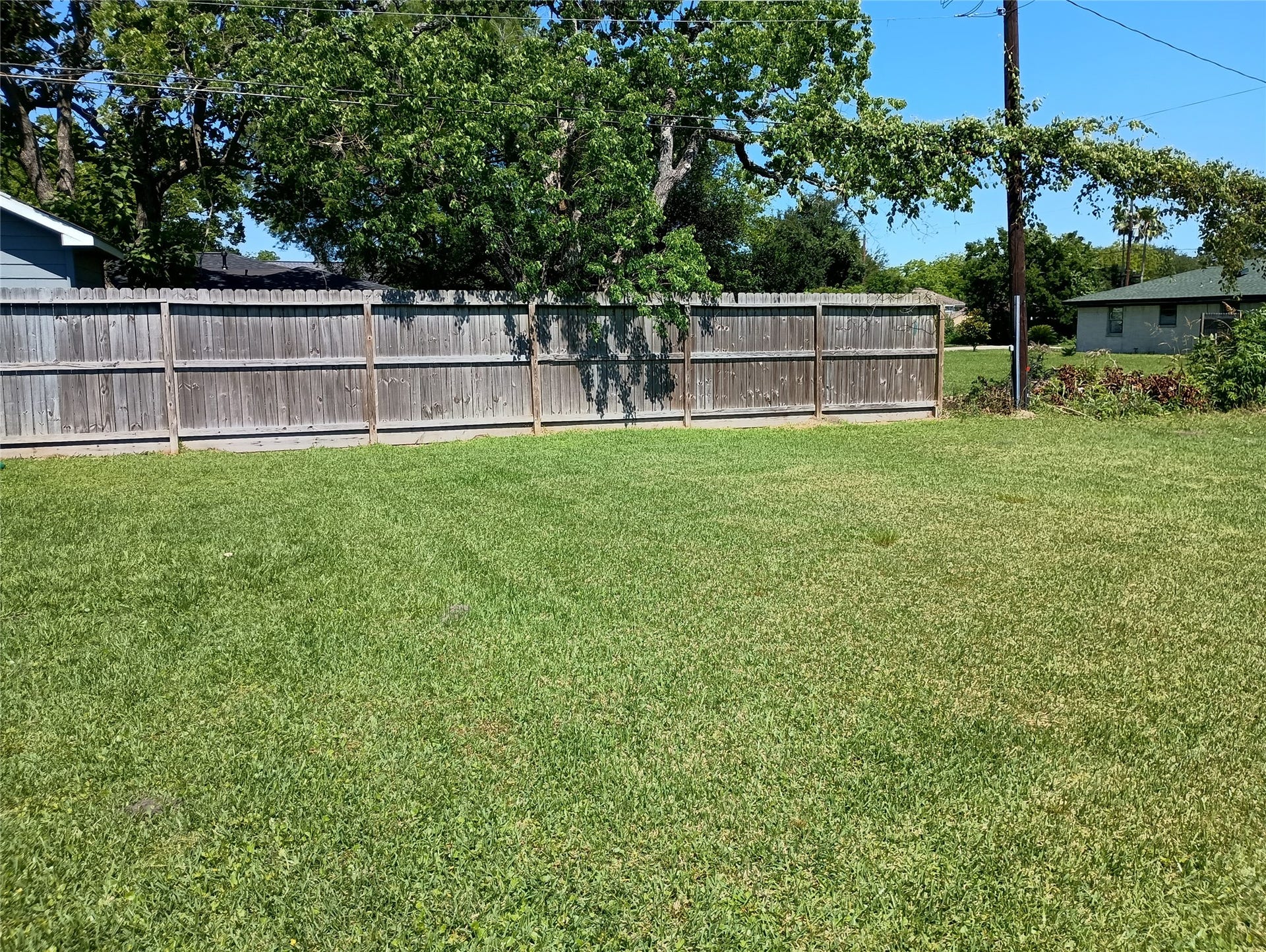 0 Fairwood Road, Hitchcock, TX 77563 The front of the lot facing the backyard. A neighbor's wooden fence covers most of the back of the property.