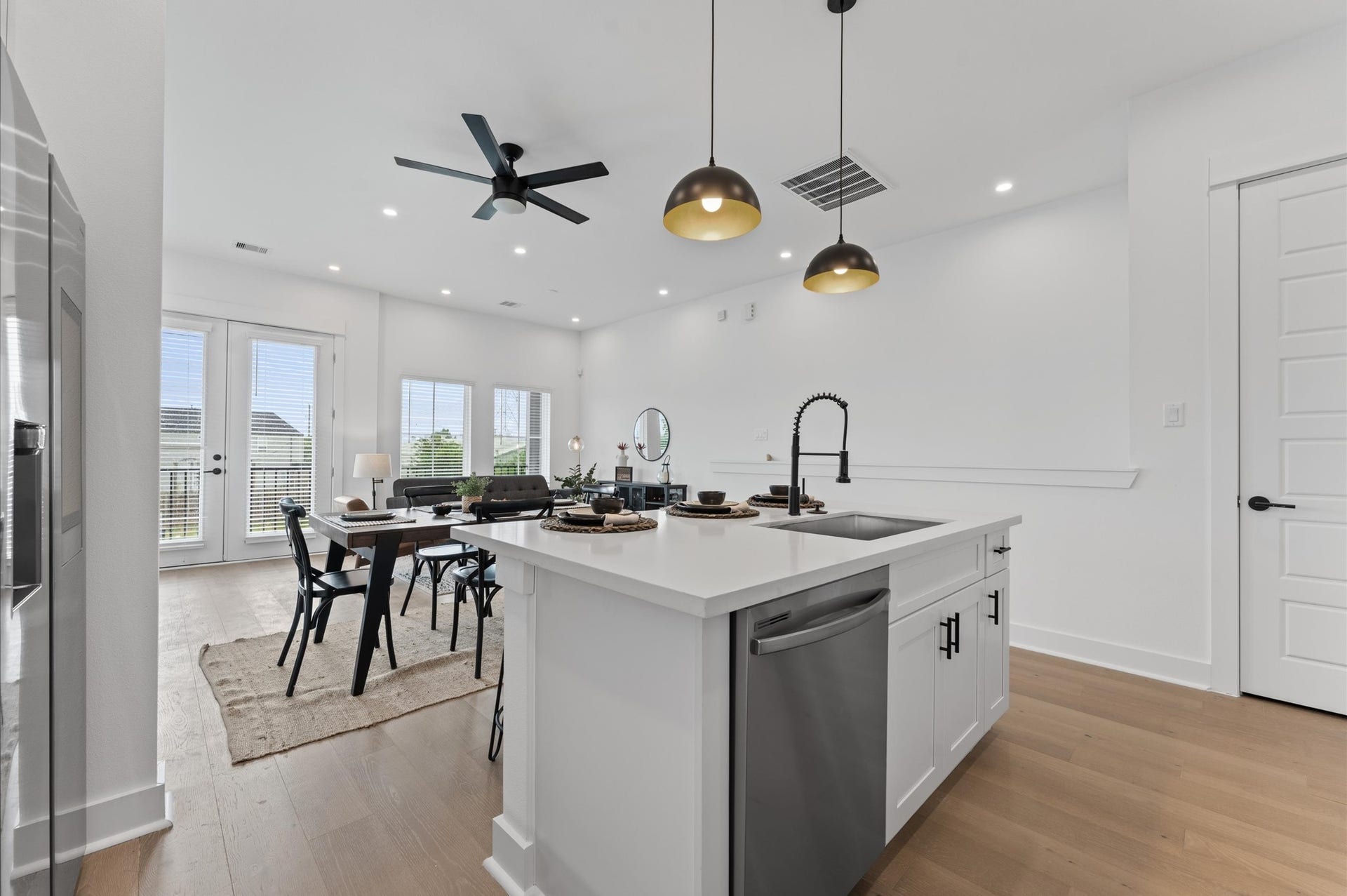 This centrally positioned kitchen island serves as a stylish anchor within the open-concept layout, offering clear sightlines to the dining area, living space, and the balcony beyond. Its placement encourages seamless interaction, whether prepping meals or entertaining guests, while natural light pours in through the nearby windows. The islands sleek design and functional surface make it a hub of activity tying together comfort and sophistication.
