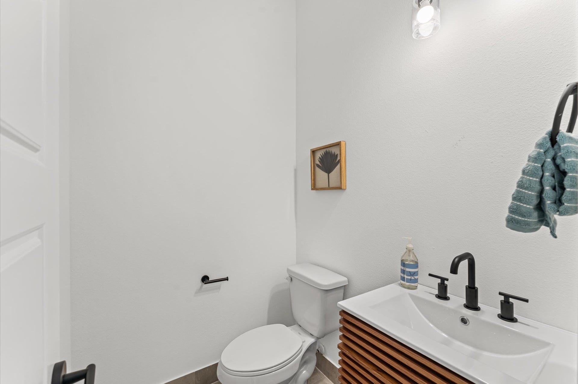Tucked conveniently near the living area, this powder room blends accessibility with sleek contemporary style. Clean lines and modern fixtures define the space, from the minimalist vanity to the streamlined sink and faucet.