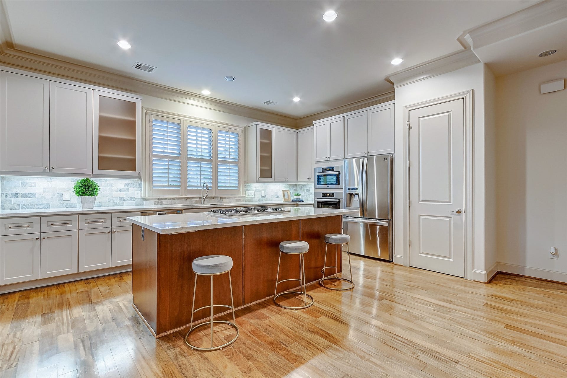 1955 Sheridan Street, Houston, TX 77030 Spacious modern kitchen featuring sleek white cabinetry, a large center island with seating, and stainless steel appliances, all illuminated by recessed lighting.