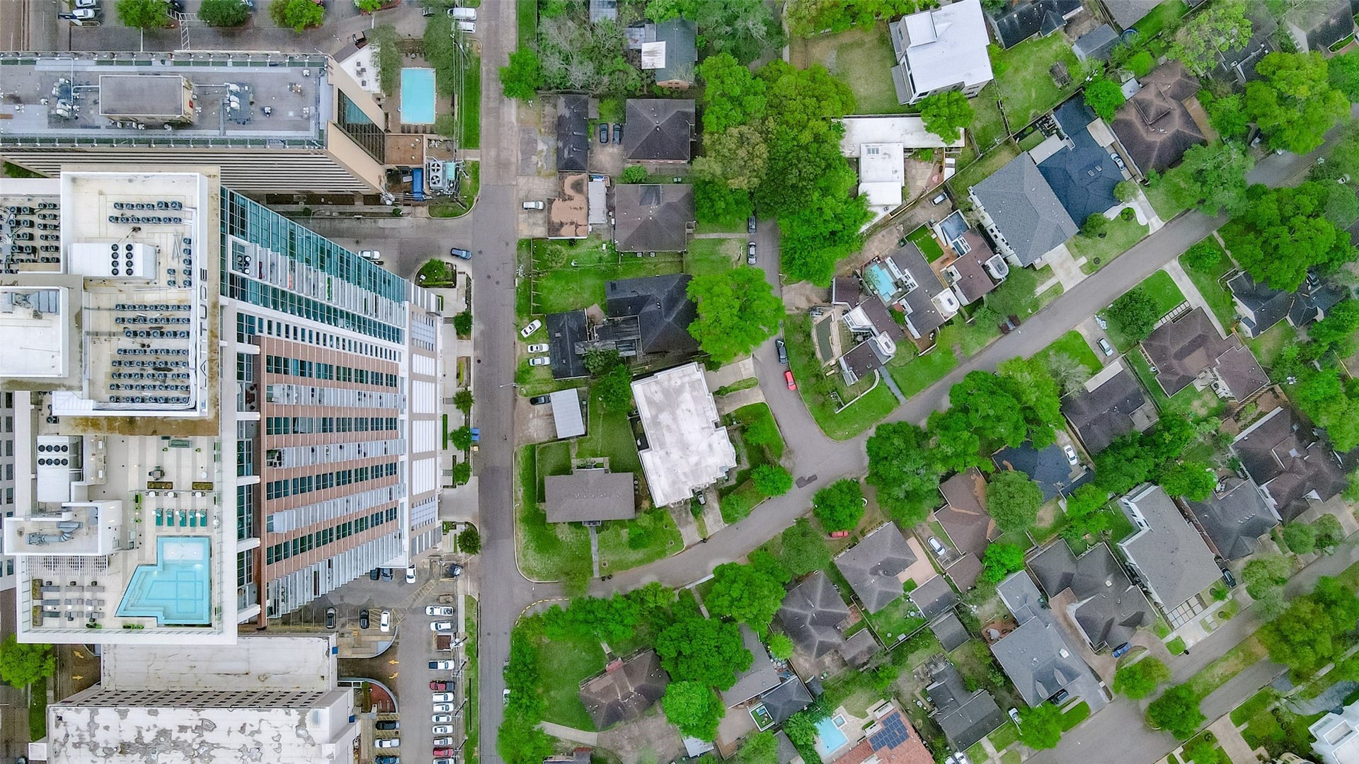 1955 Sheridan Street, Houston, TX 77030 Aerial view showcasing a vibrant neighborhood with a blend of modern high-rise buildings and charming residential homes, surrounded by lush greenery.