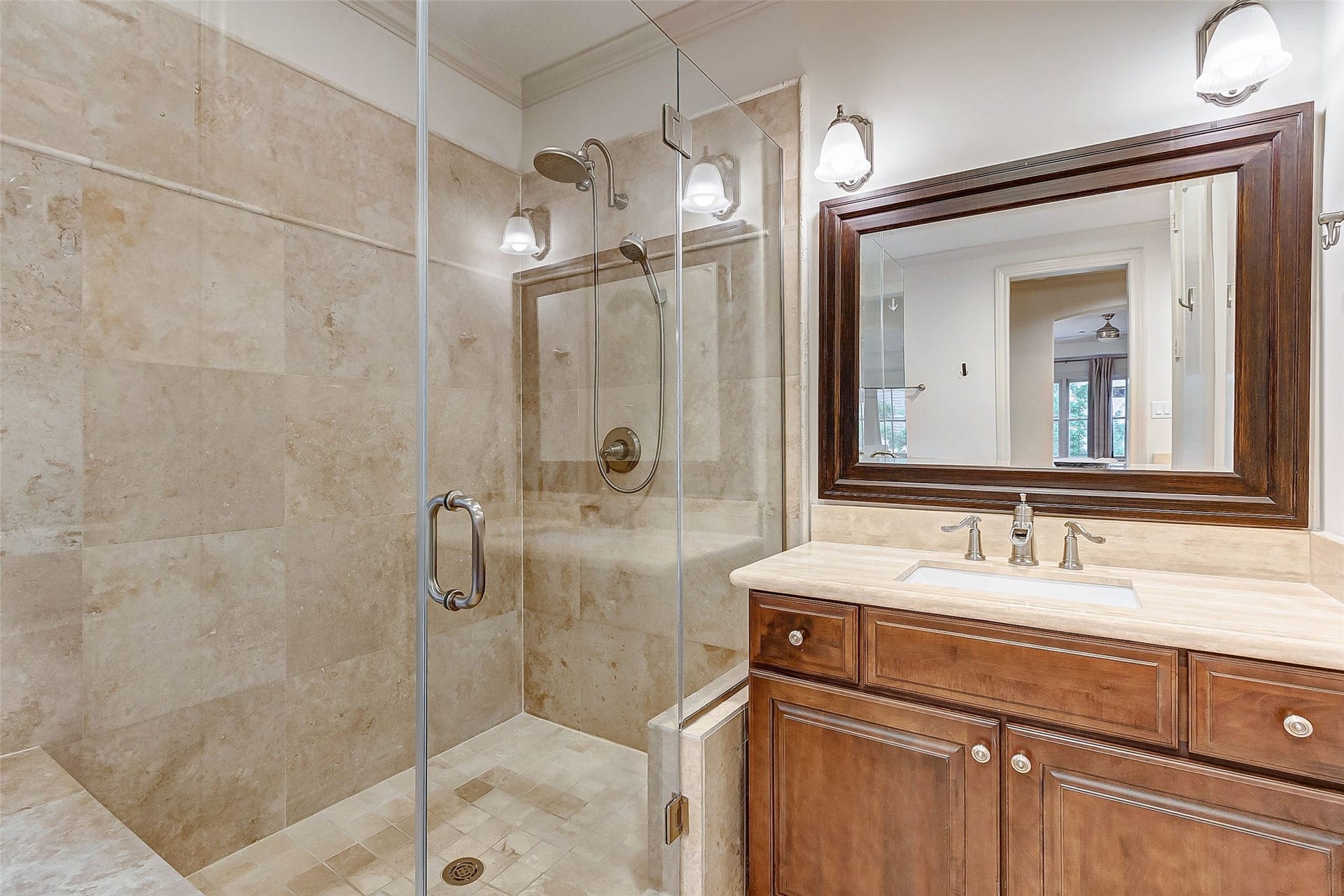 1955 Sheridan Street, Houston, TX 77030 Luxurious bathroom featuring a spacious glass-enclosed shower with elegant tile work, complemented by a sleek vanity with a large framed mirror and modern lighting.
