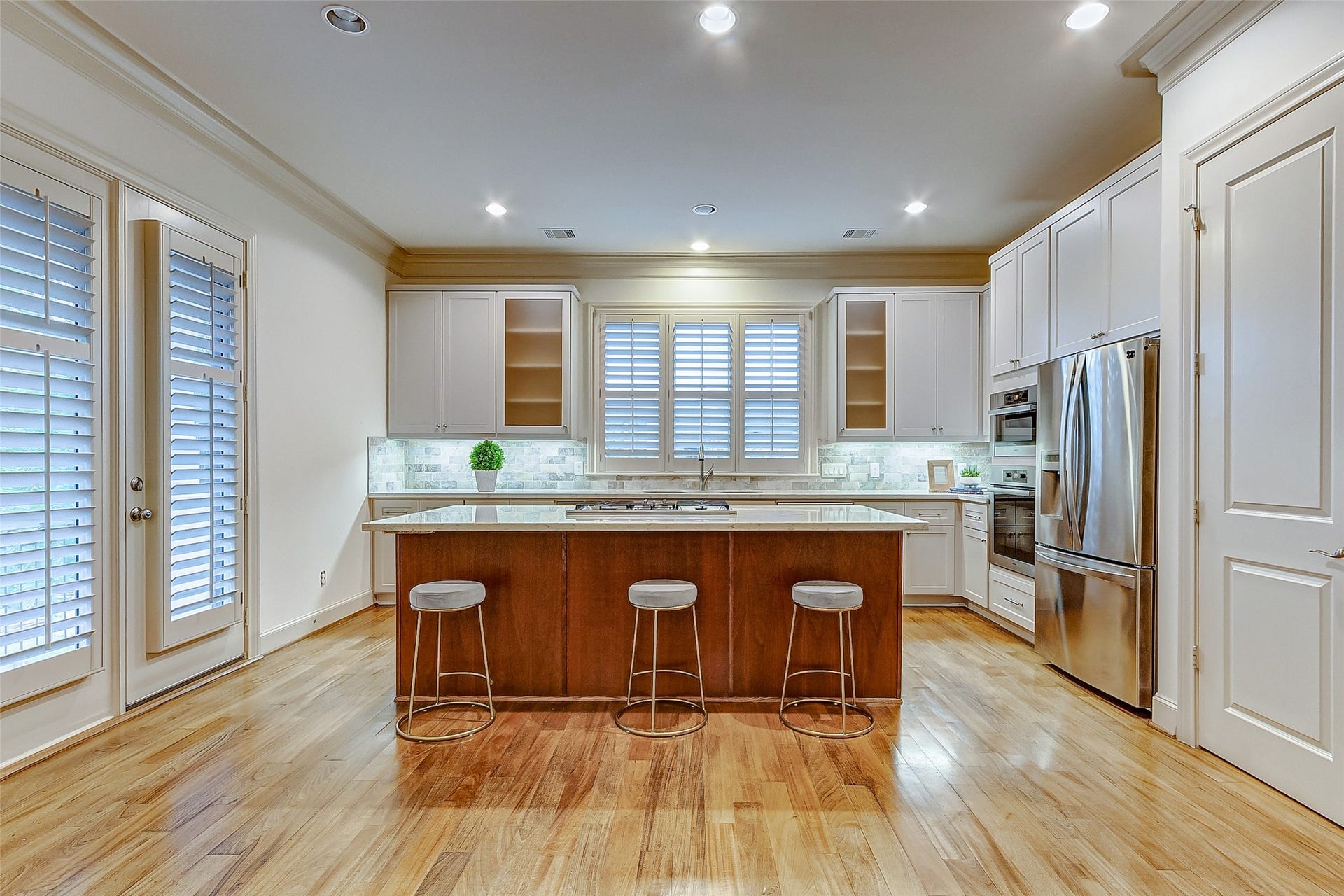 1955 Sheridan Street, Houston, TX 77030 Spacious kitchen with sleek stainless steel appliances, a central island with seating, and elegant cabinetry, all illuminated by soft recessed lighting.