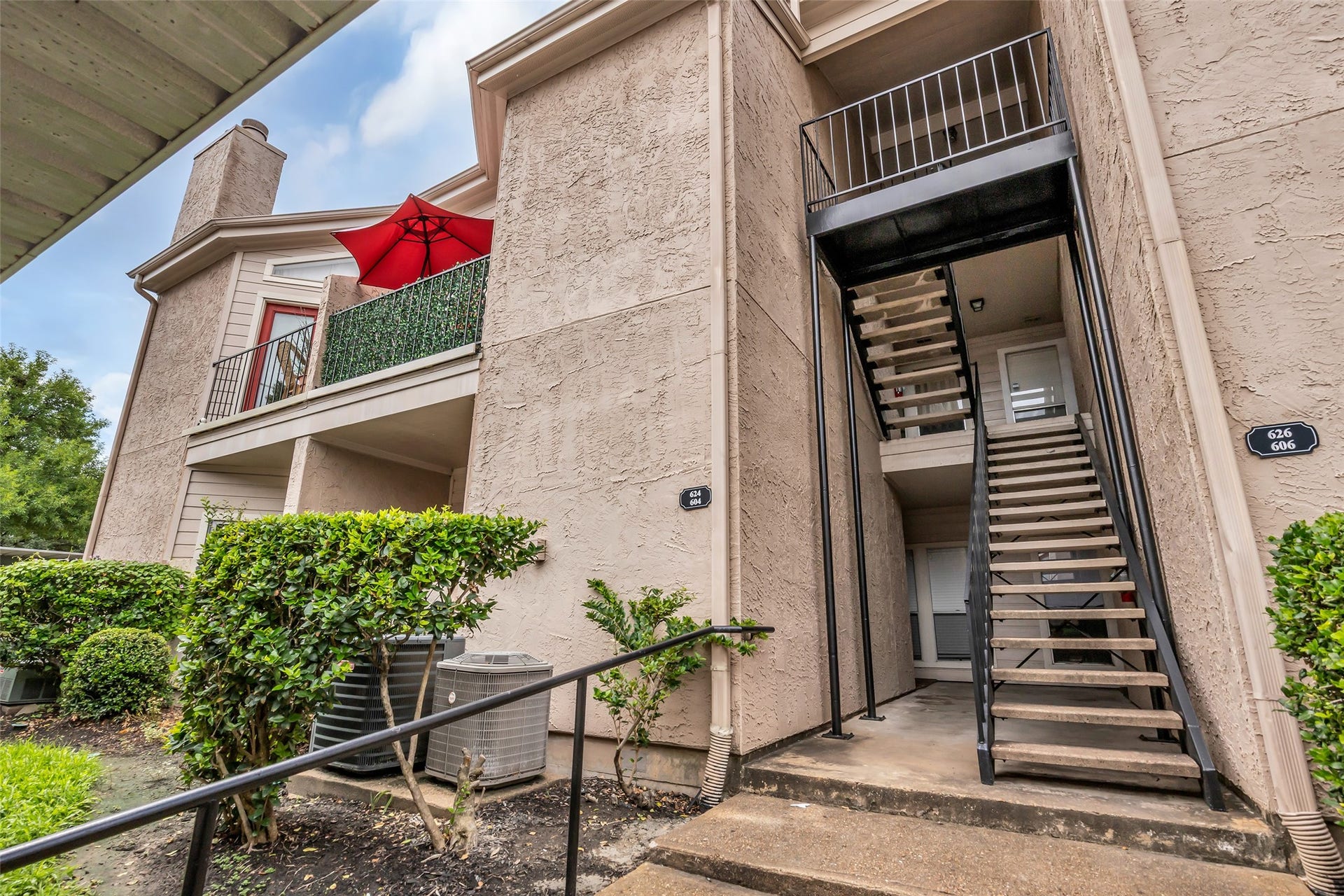 10855 Meadowglen Lane, #604, Houston, TX 77042 The condo entrance features an inviting exterior with a combination of wood and brick, creating a warm and classic look.