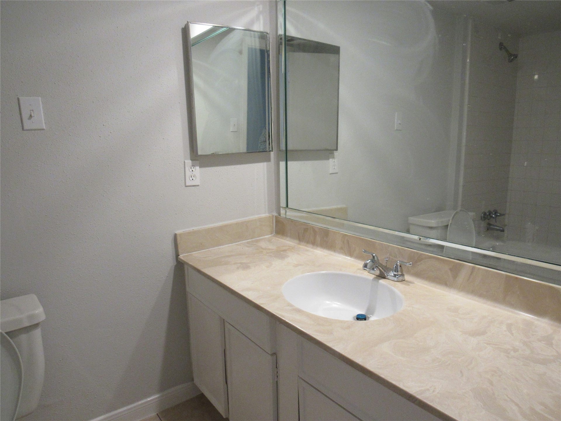 Hall bathroomwith medicine cabinet, single sink, man-made marble counter, cammode, & tub