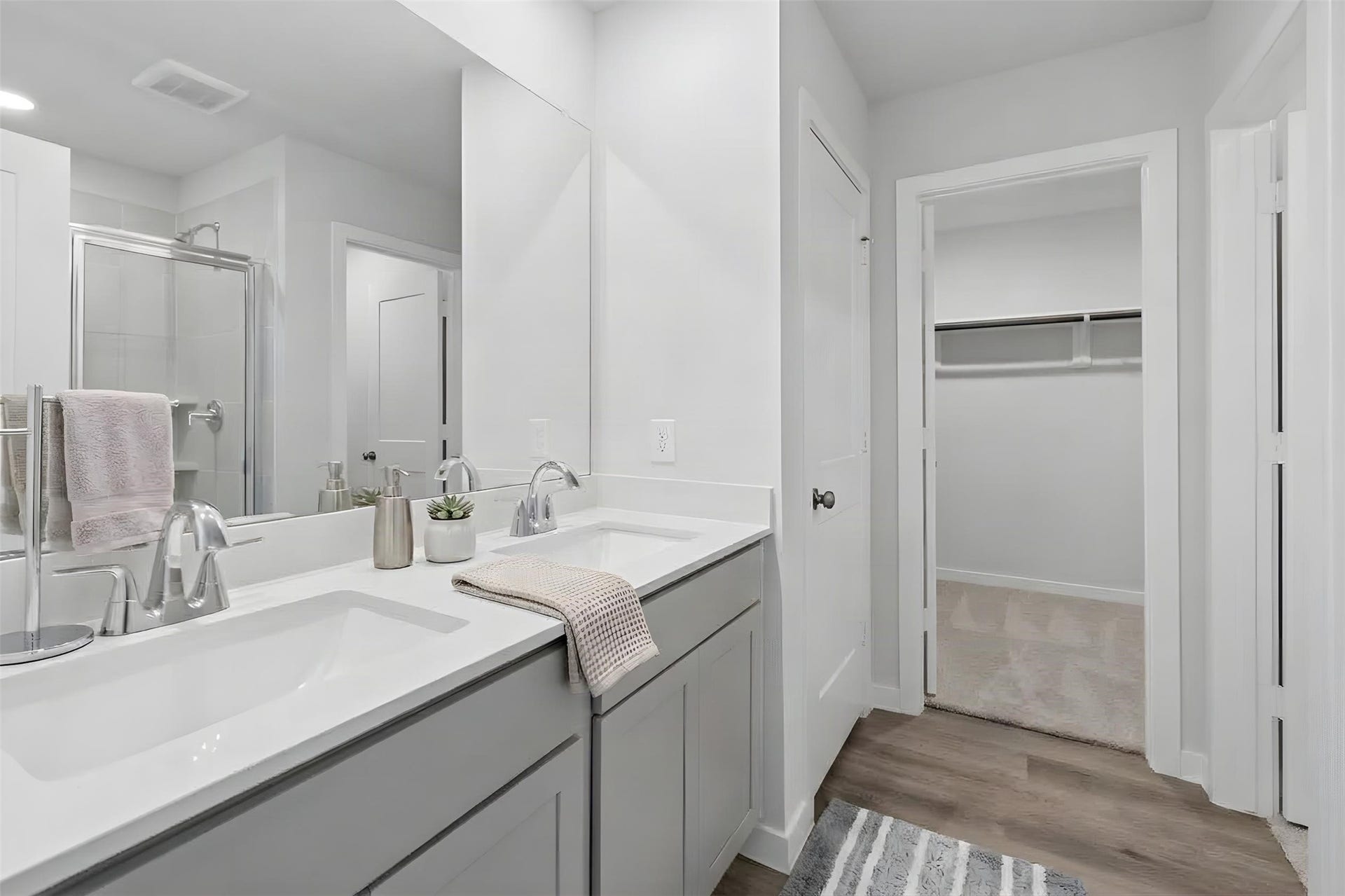 Experience luxury in the primary bath, featuring a sleek double vanity, elegant fixtures, and seamless access to a spacious walk-in closet.