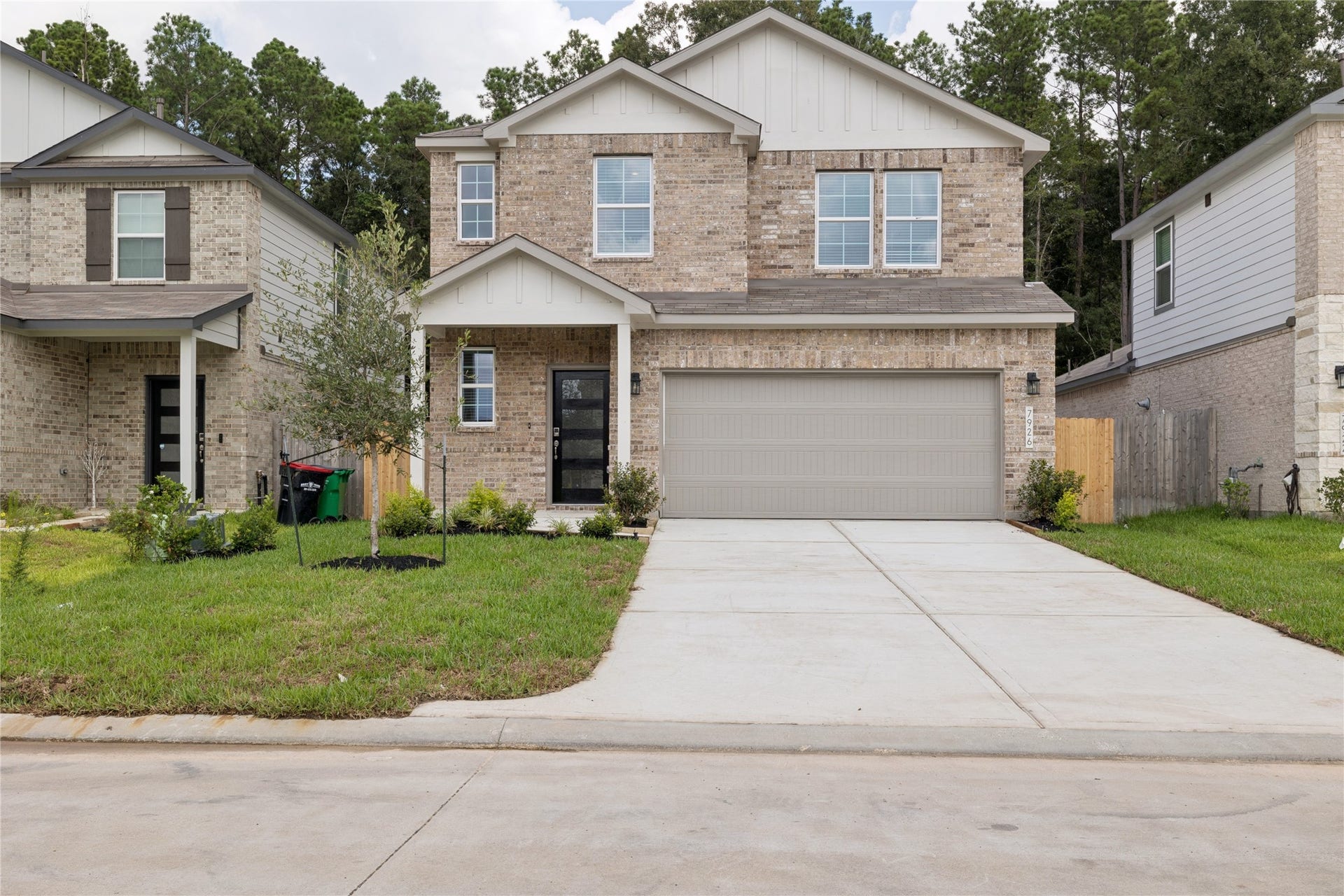 Charming two-story brick home with a double garage and inviting front entrance, nestled in a quiet neighborhood with lush greenery.