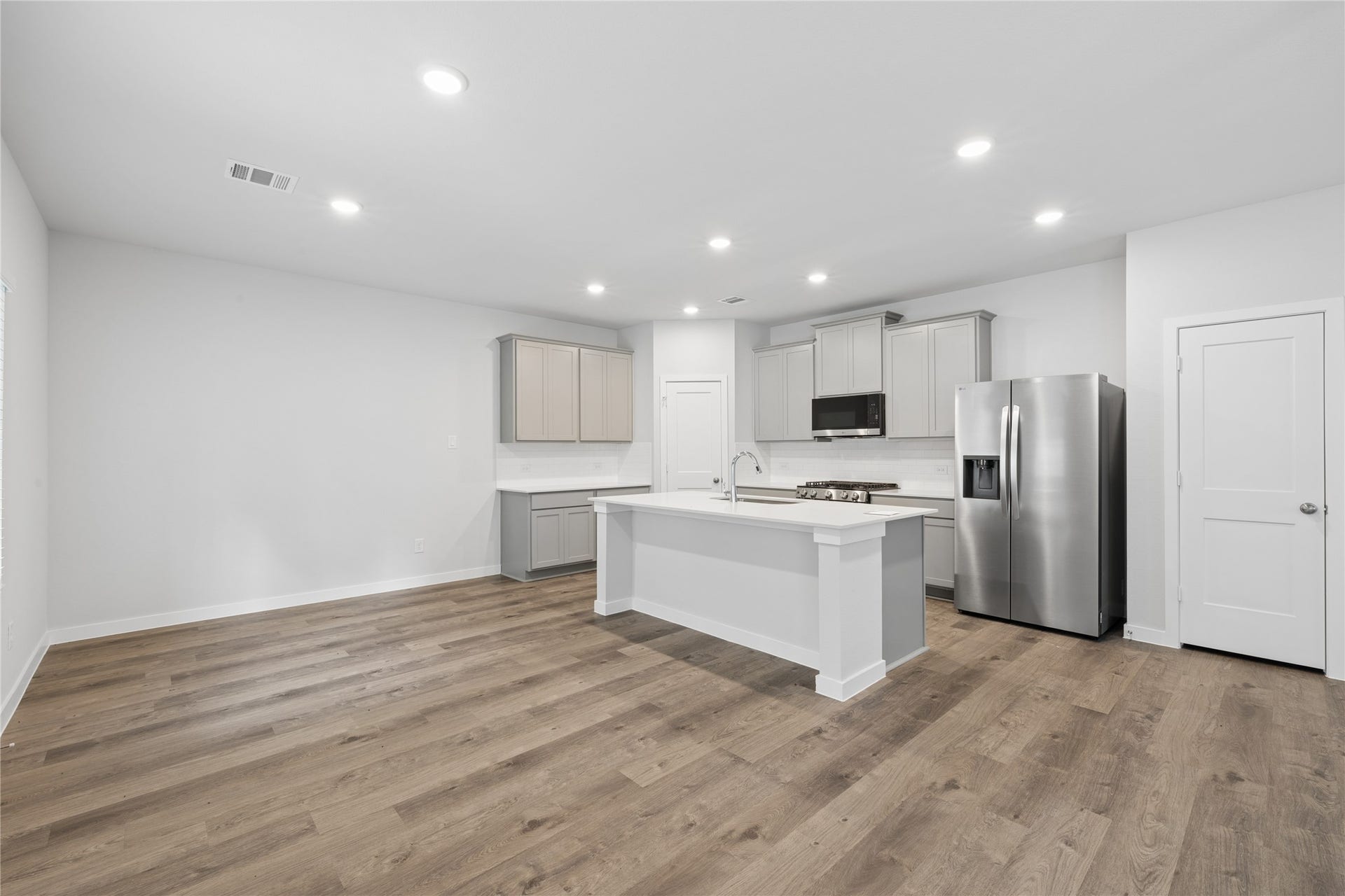 Spacious modern kitchen with sleek stainless steel appliances, stylish cabinetry, and a central island, complemented by elegant wood flooring.