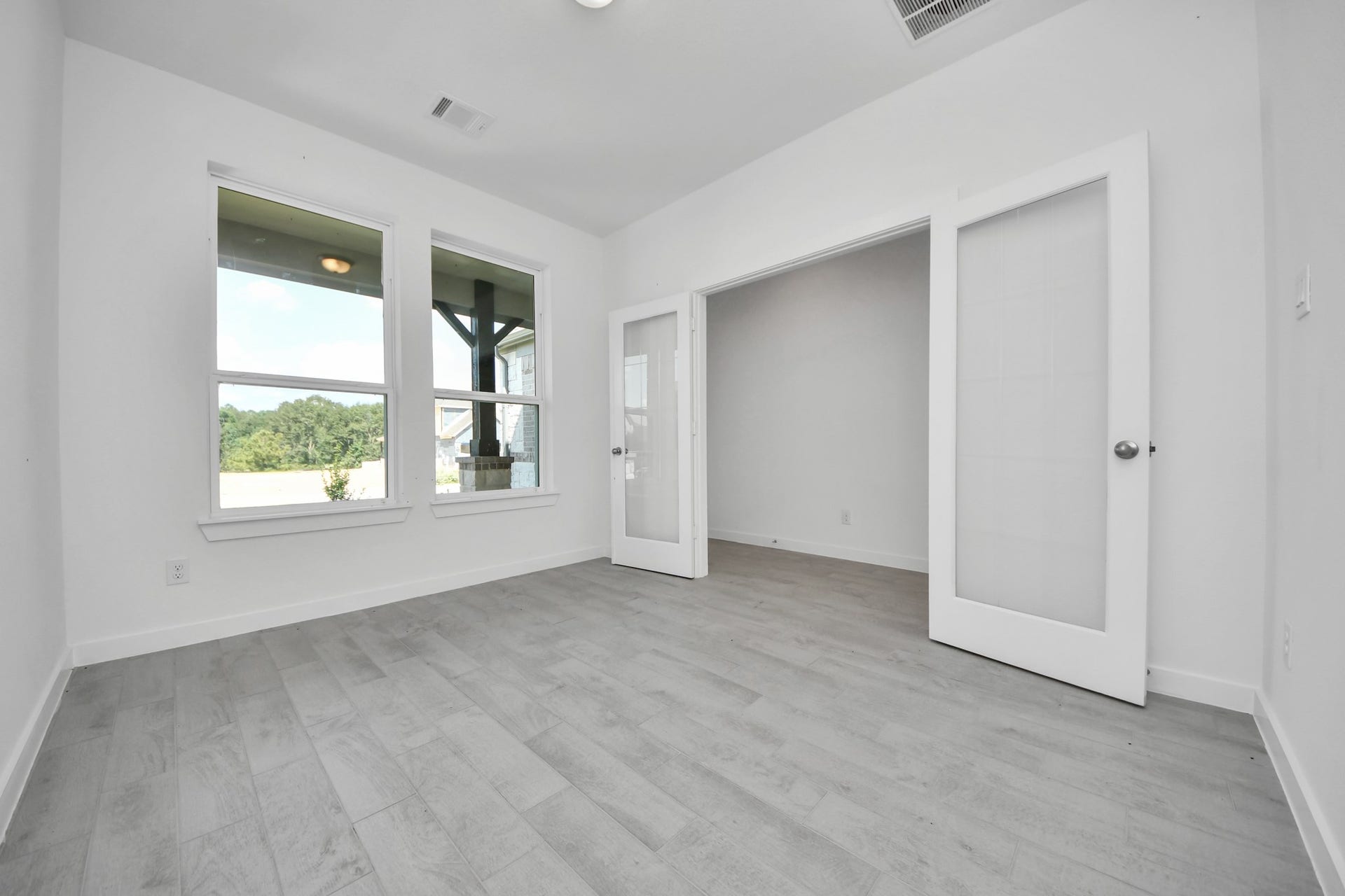 3072 Spoolwood Trail, Magnolia, TX 77355 Experience the perfect blend of sophistication and warmth in this home office, boasting elegant wood-look tile flooring and flooded with natural light from expansive windows and French doors.