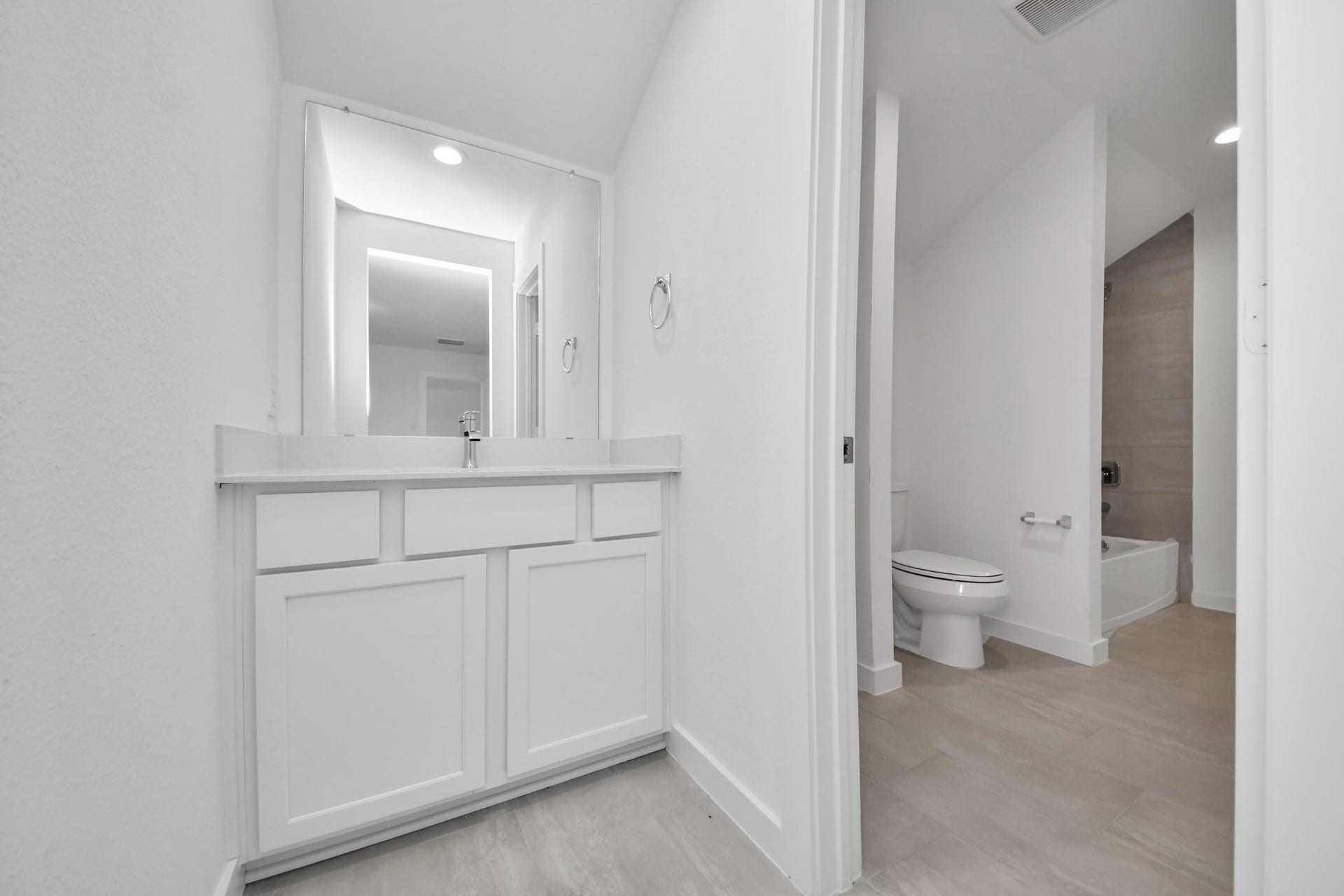 3072 Spoolwood Trail, Magnolia, TX 77355 Experience convenience in the secondary bathroom, designed for Jack and Jill arrangements, now with a separate vanity area. This well-appointed space showcases stylish tile flooring, a bath/shower combo with an elegant tile surround, and light-stained wood cabinets. The beautiful light countertop adds a touch of sophistication, combining functionality and aesthetics seamlessly.