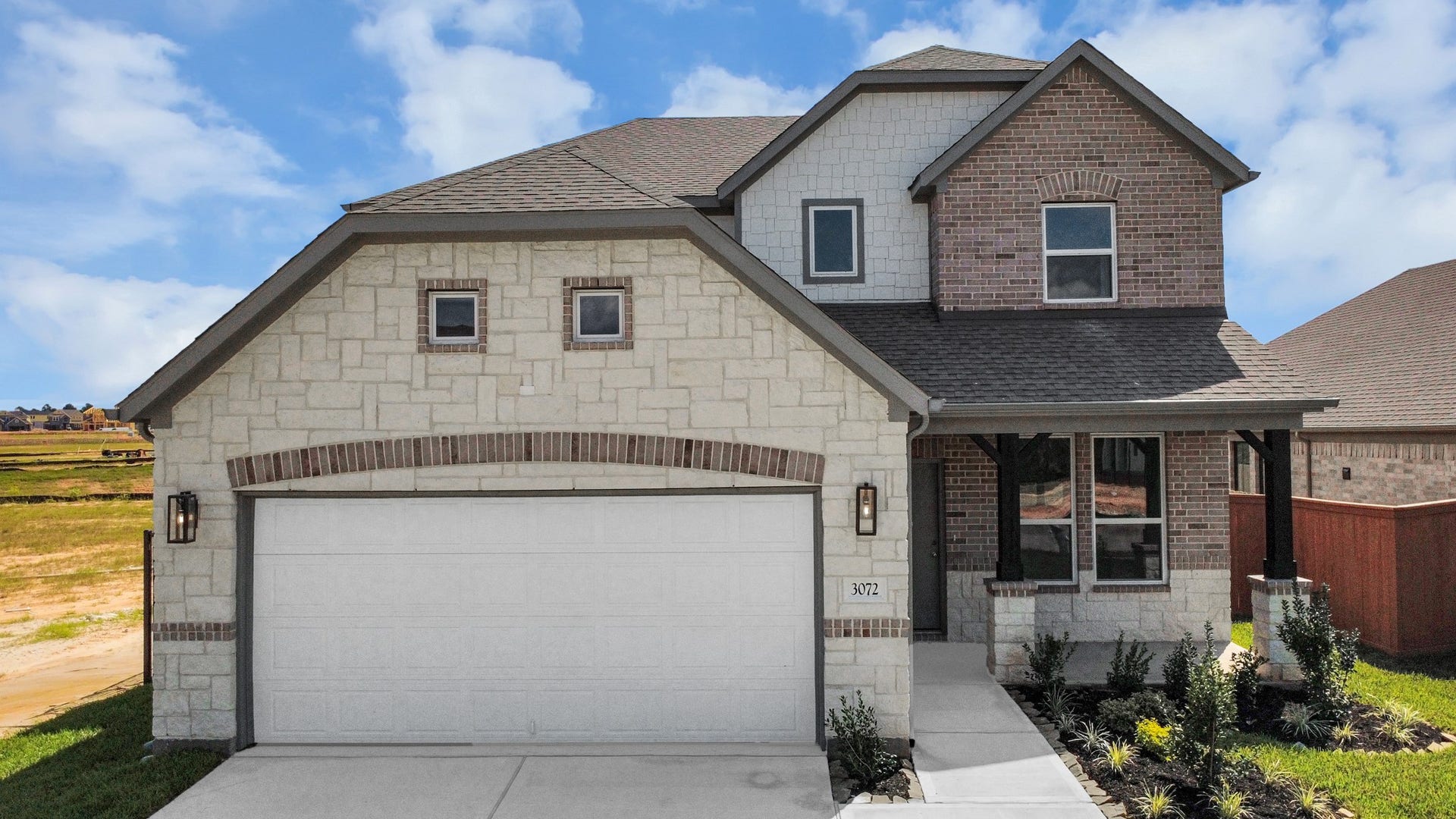 3072 Spoolwood Trail, Magnolia, TX 77355 Meticulously maintained yard and lush landscape, paired with a premium elevation featuring captivating brick accents. Modern coach lights add a touch of contemporary elegance to the exterior.