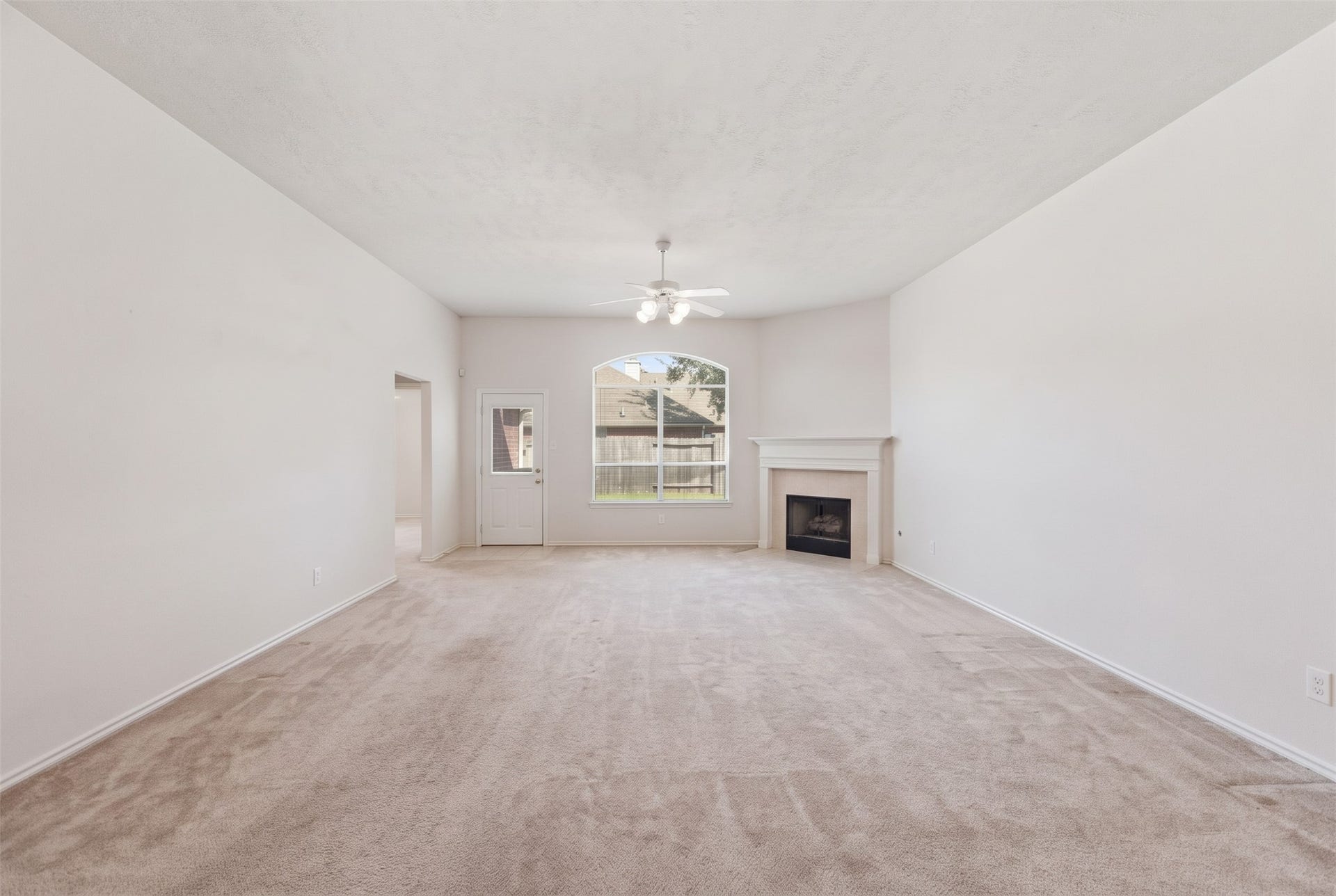 2426 Floral Ridge Drive, Spring, TX 77388 Spacious living room featuring neutral carpeting, a cozy fireplace, and abundant natural light from large windows.