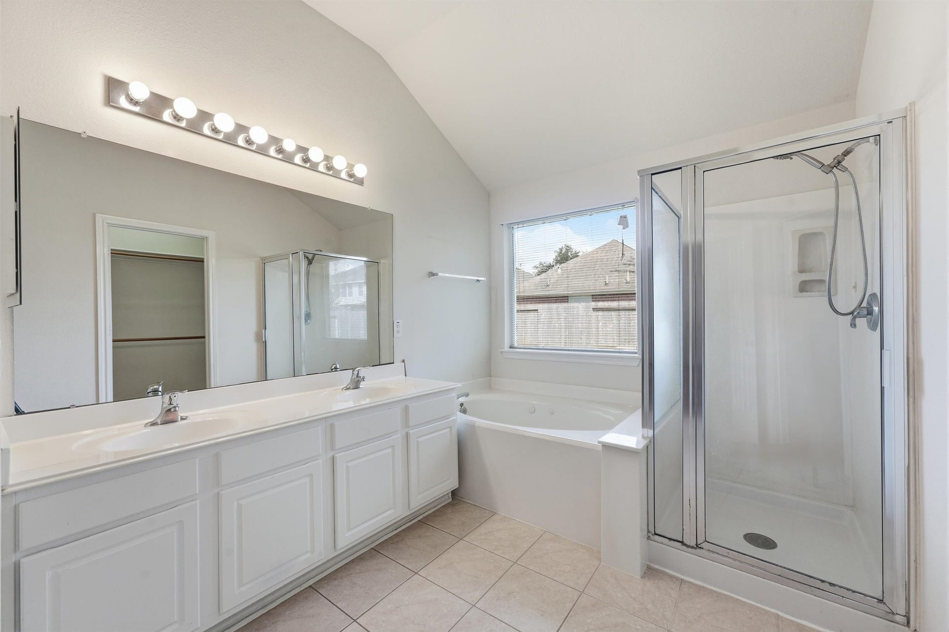 2426 Floral Ridge Drive, Spring, TX 77388 Spacious bathroom featuring a double vanity, large mirror with ample lighting, a relaxing bathtub, and a separate glass-enclosed shower.