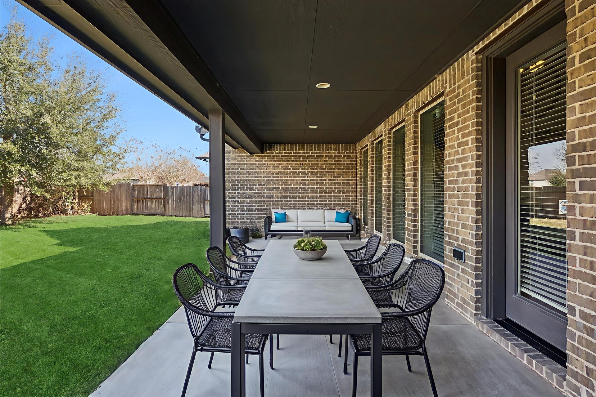 The deep covered patio serves as a shaded sanctuary, extending your living space into the outdoors while providing shelter from the sun and rain. This area has been digitally enhanced to illustrate its potential as an elegant lounge and dining area.