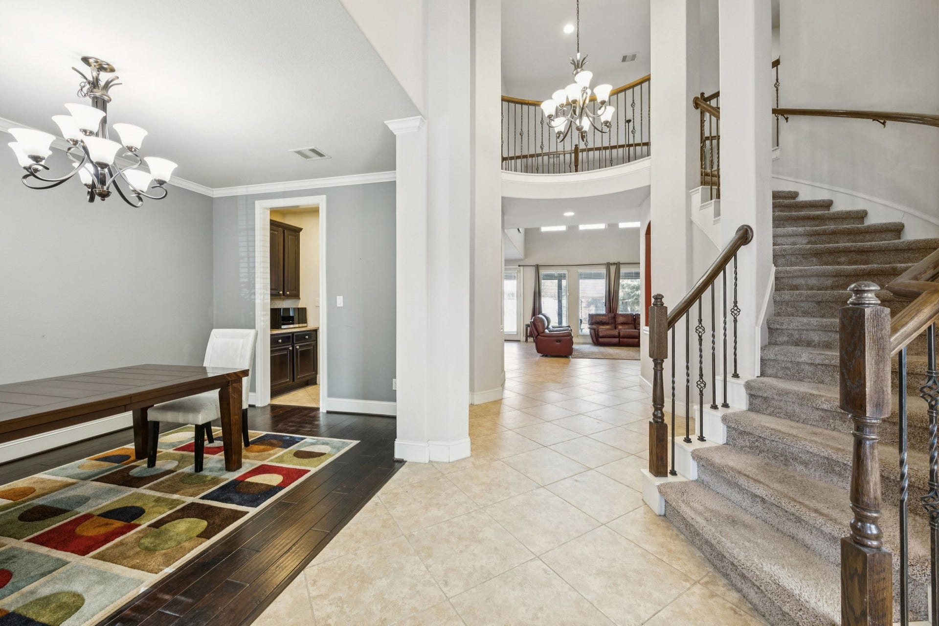 Step into a sophisticated formal entry featuring soaring high ceilings, marble floors, and an elegant wrought iron staircase.