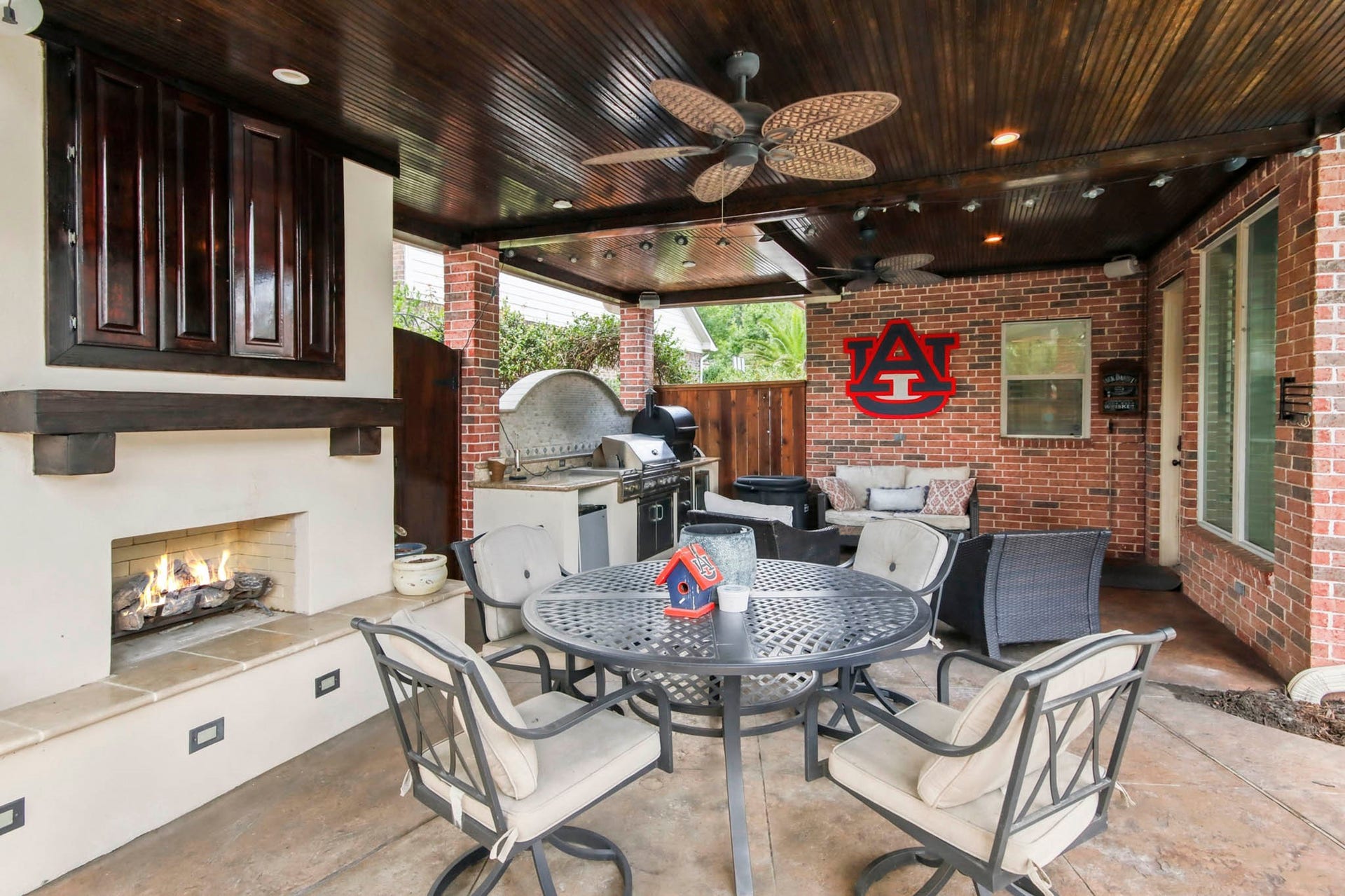 Outdoor kitchen with stainless steel grill, and mini fridge, set against a stylish stone backsplash and brick accents, perfect for entertaining.
