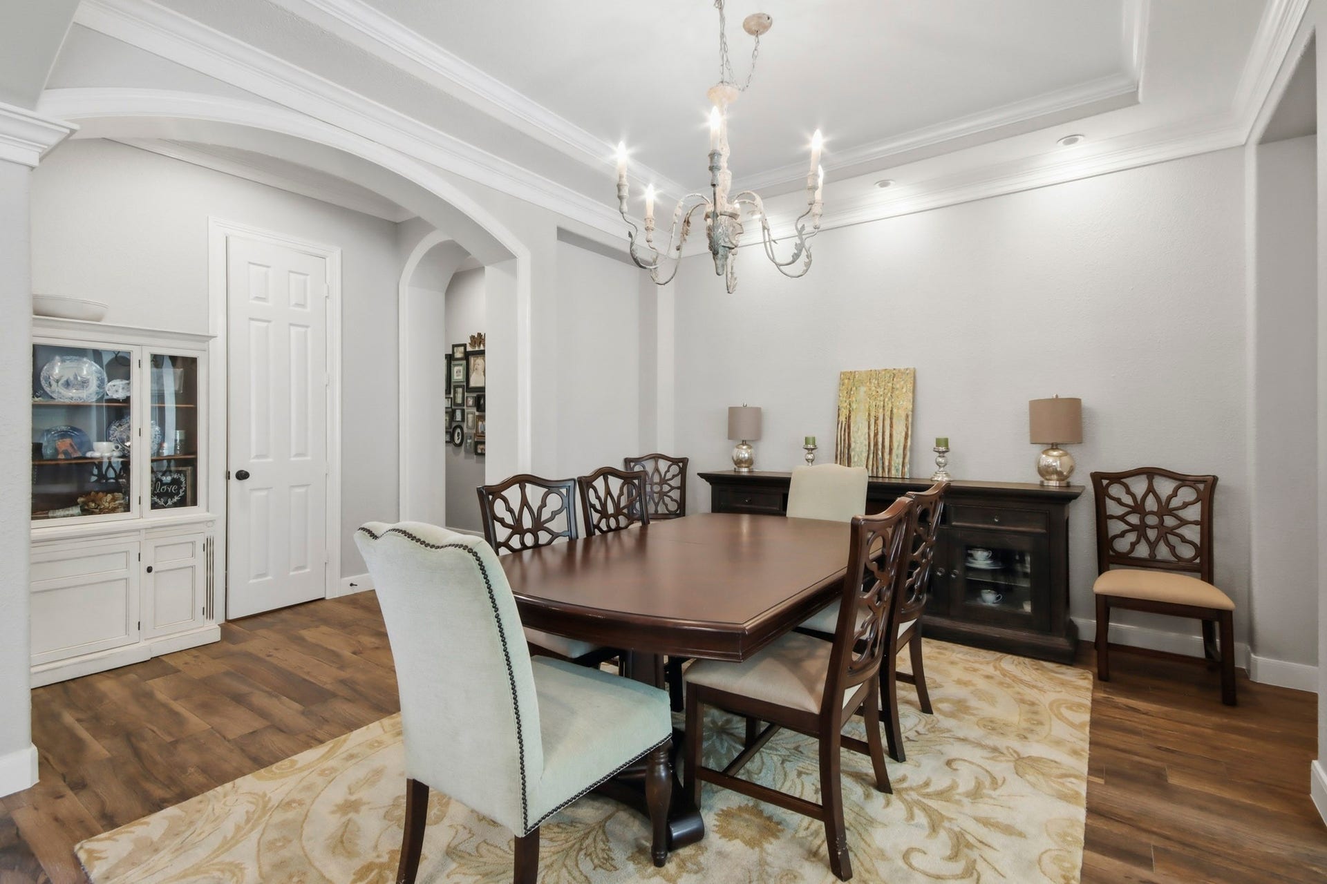 Dining room featuring an intricate chandelier, tray ceiling, and arched entry ways.