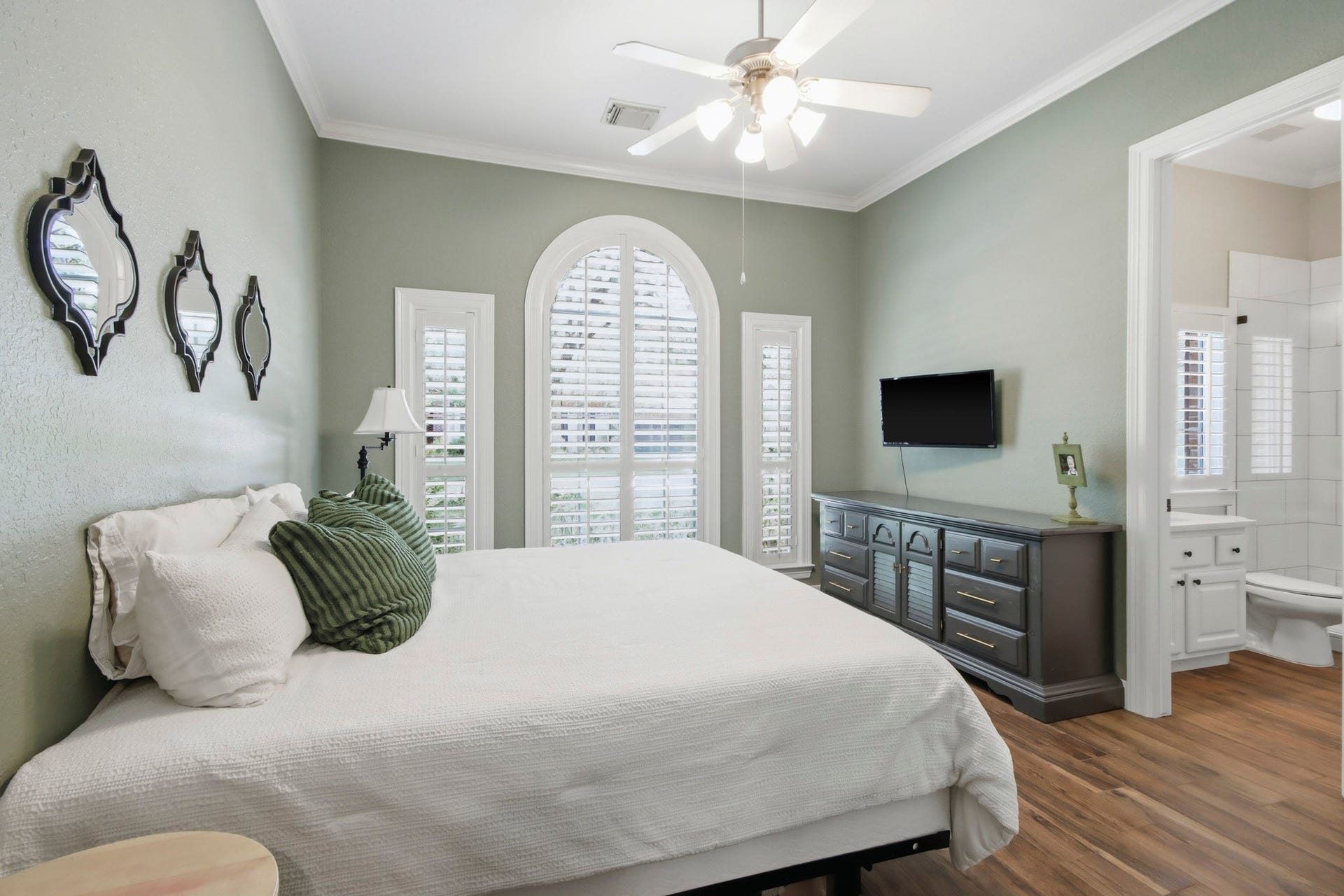 Downstairs secondary bedroom with elegant arched window, abundant natural light, and an en-suite bathroom for added convenience.