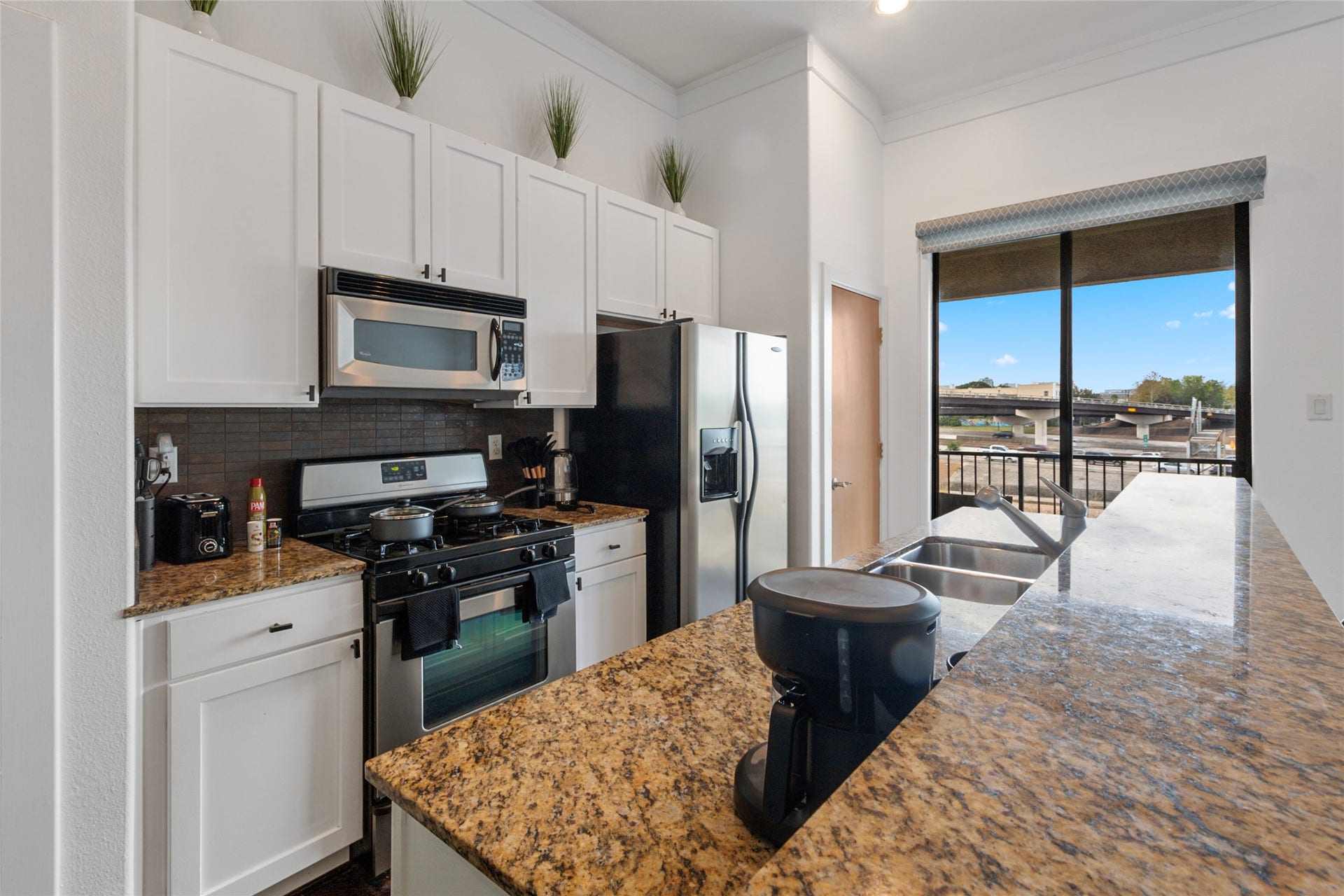 Kitchen with granite island, stainless appliances, and balcony access